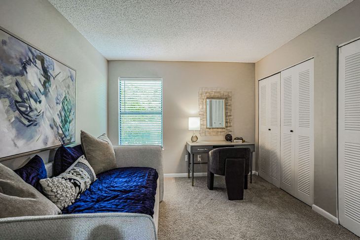 Cozy home office with a daybed, desk, and decorative closet doors. Soft colors and natural light.