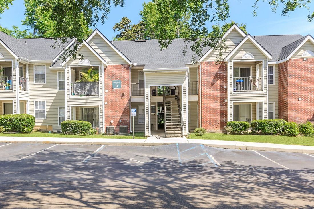 Apartment building with beige siding, brick accents, balconies, and a handicap parking space.