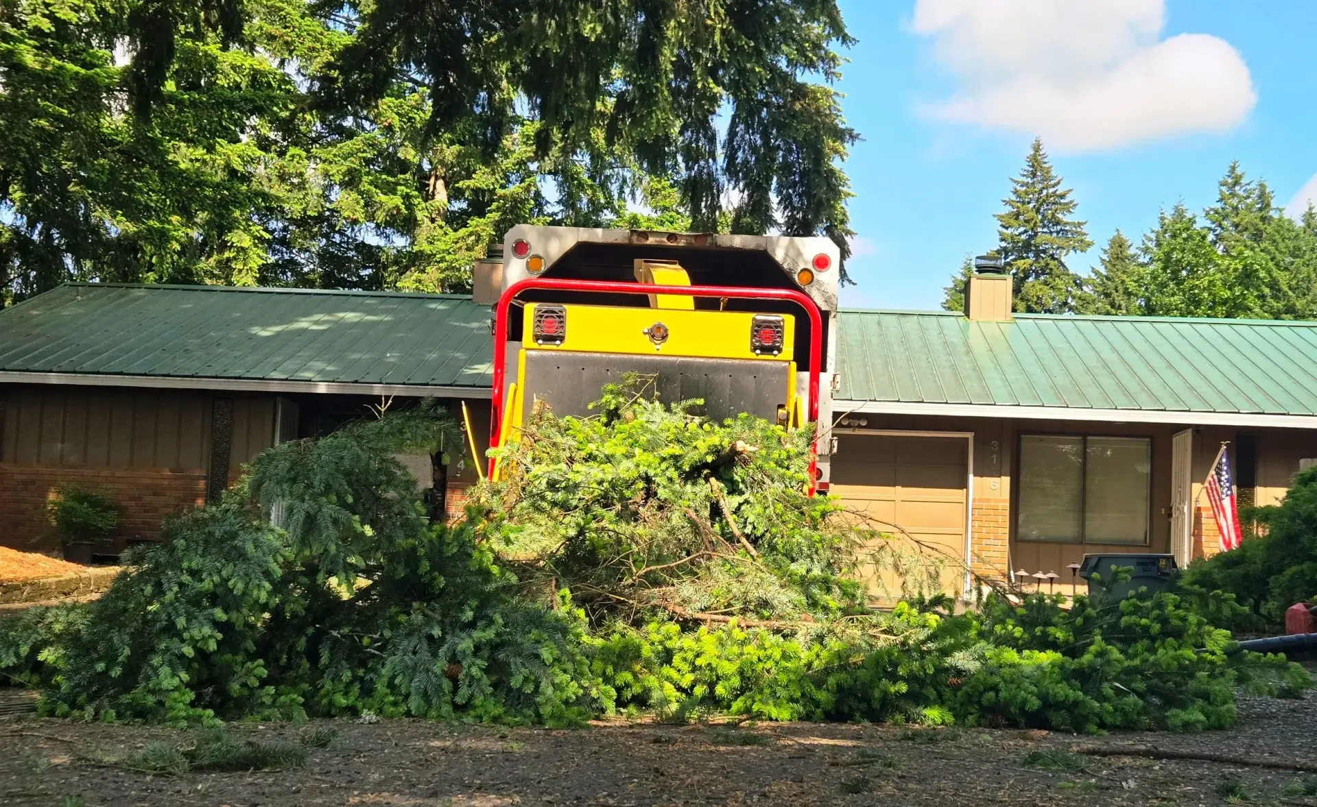 A yellow truck is parked in front of a house with a green roof.
