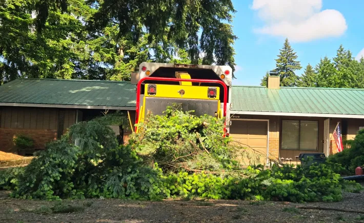 A yellow truck is parked in front of a house with a green roof.