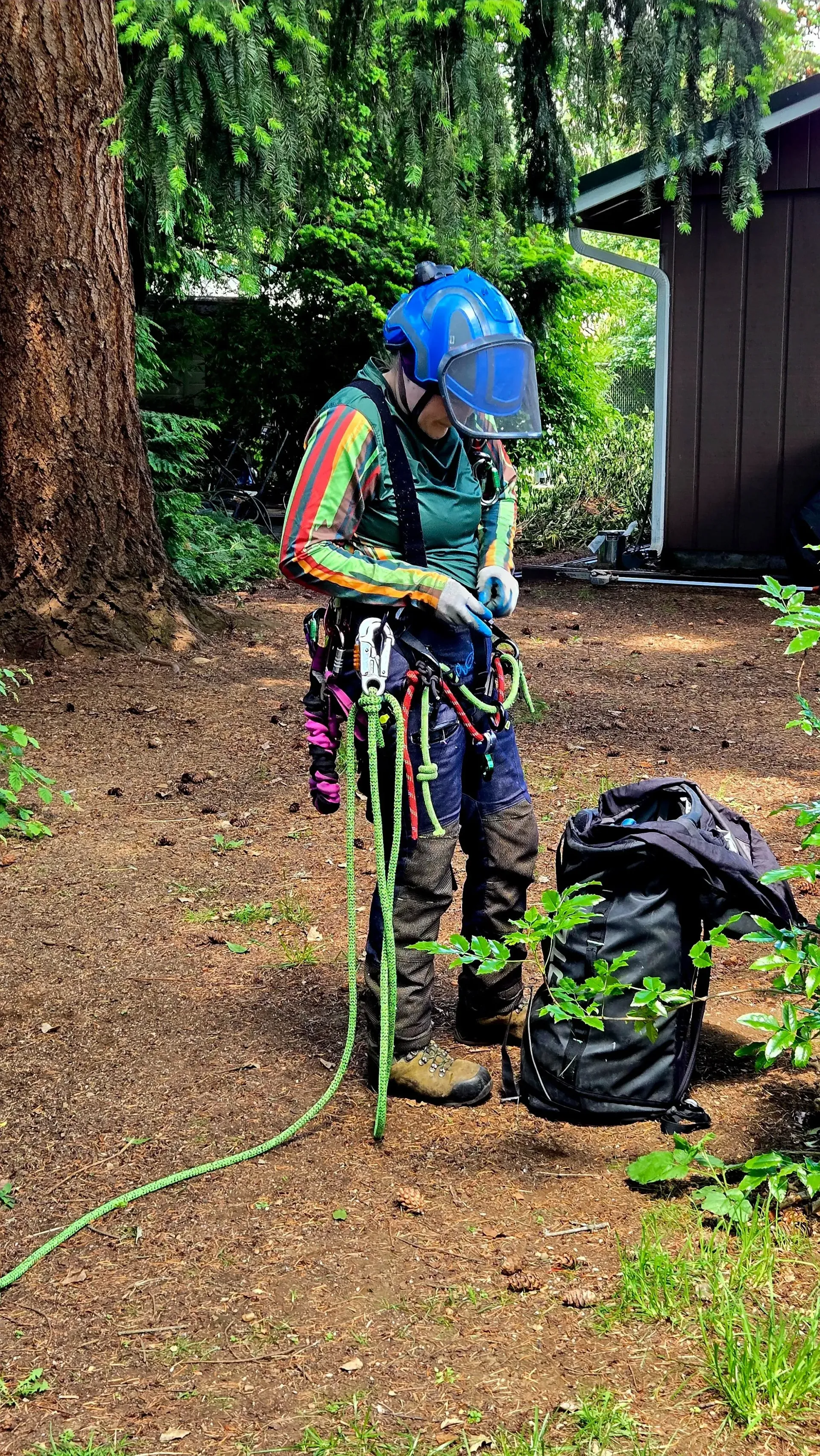 A man wearing a helmet and goggles is standing next to a tree.