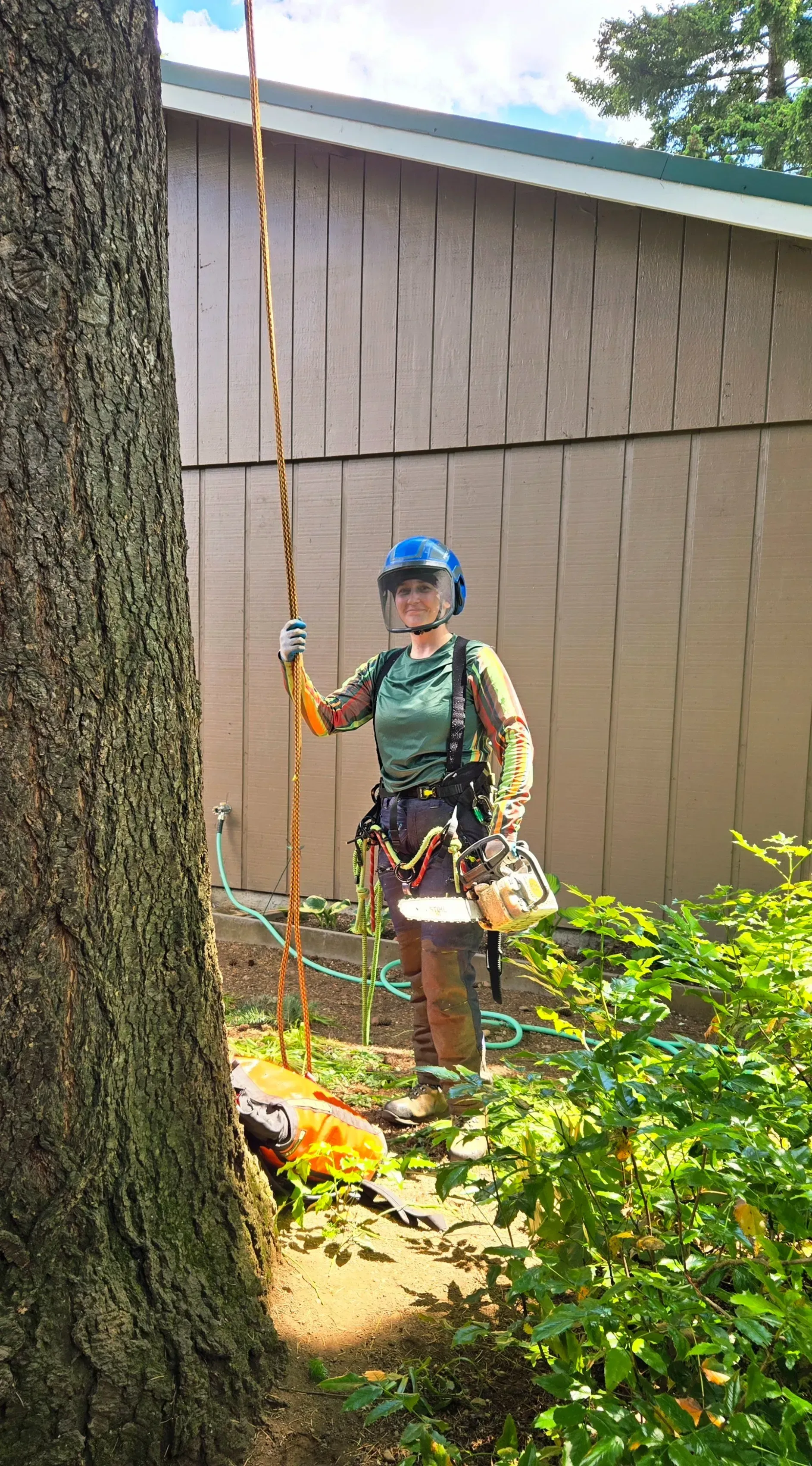 A man is standing next to a tree with a chainsaw.