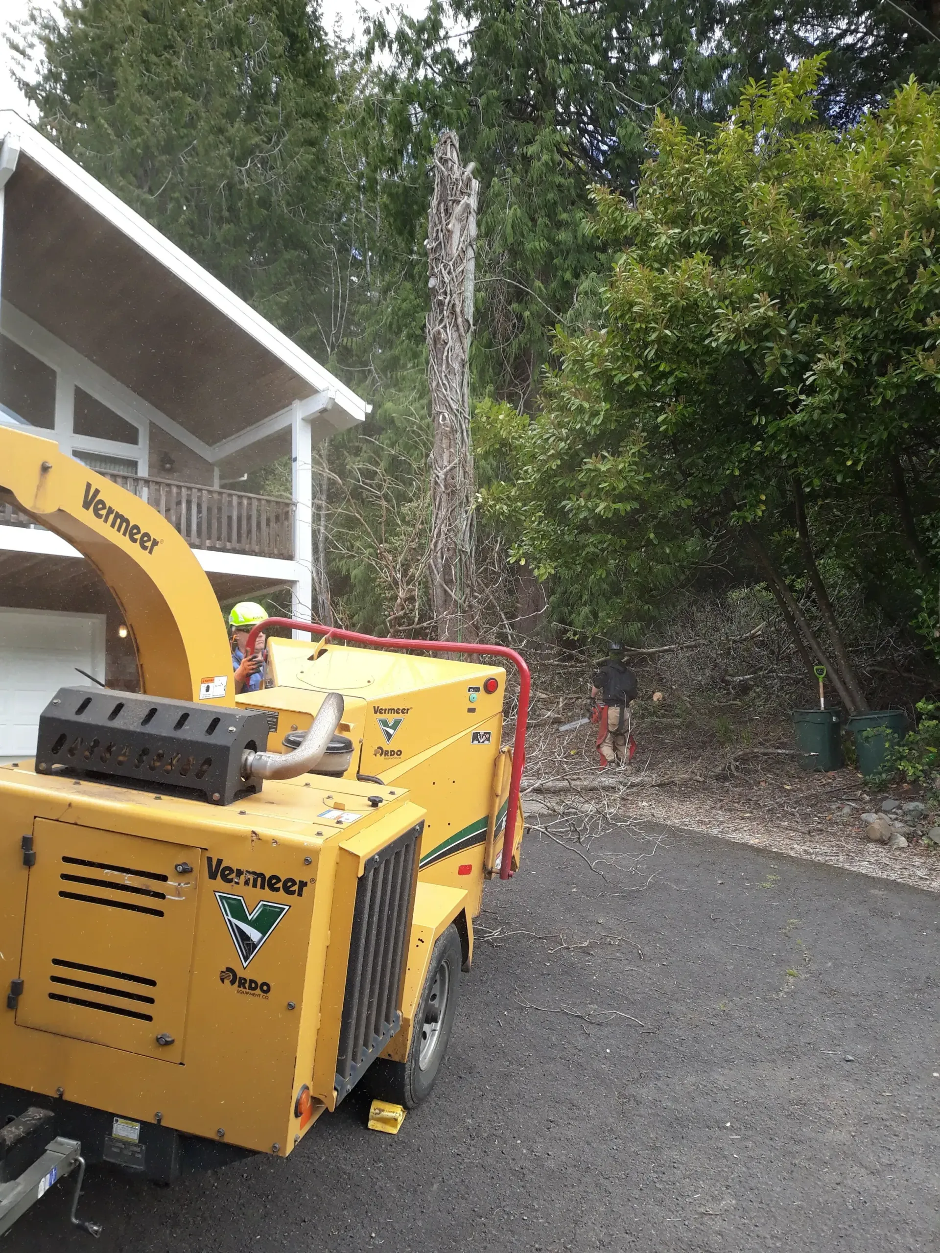A tree chipper is parked in front of a house.