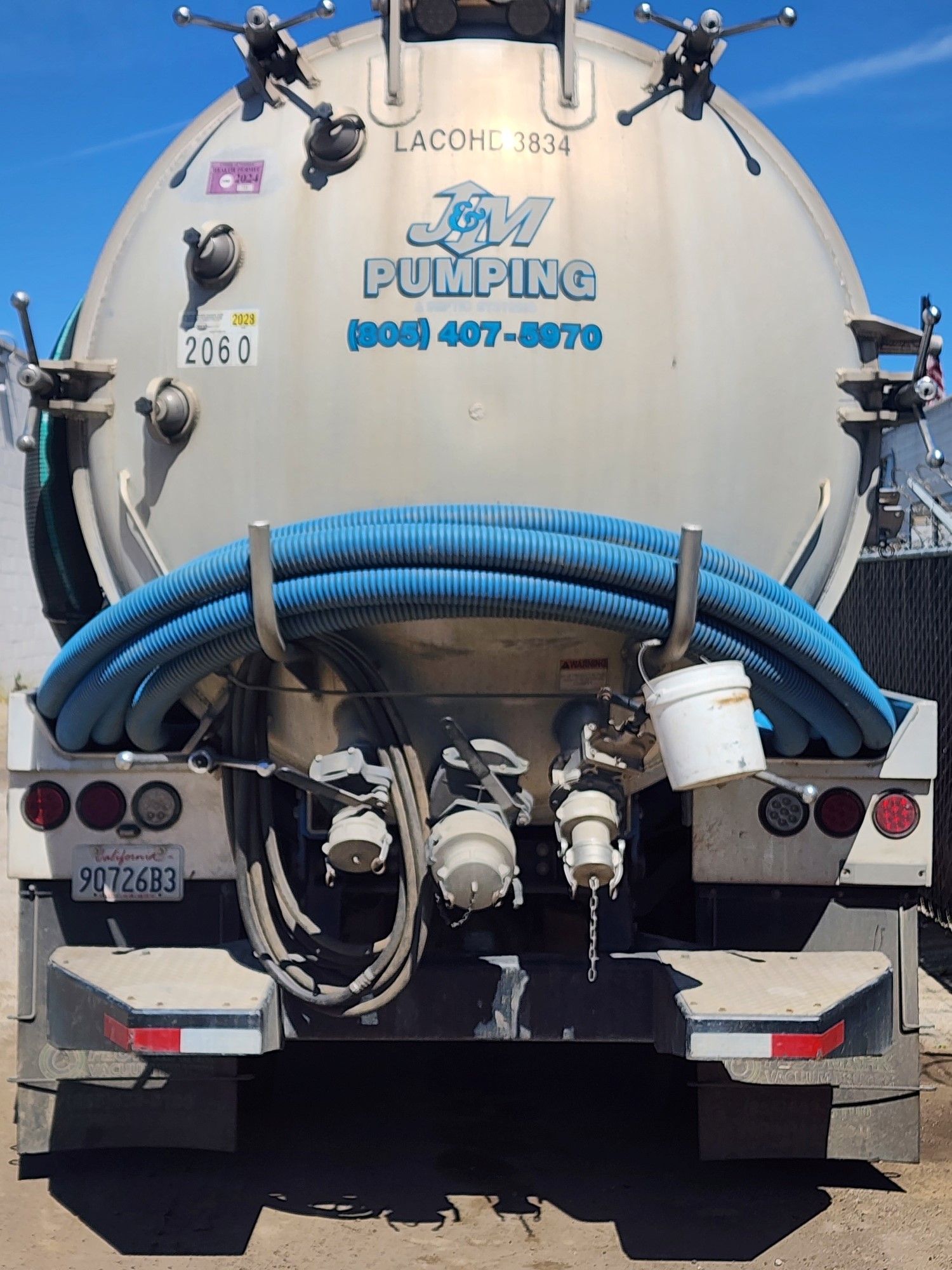 A septic tank truck with a green hose attached to it.