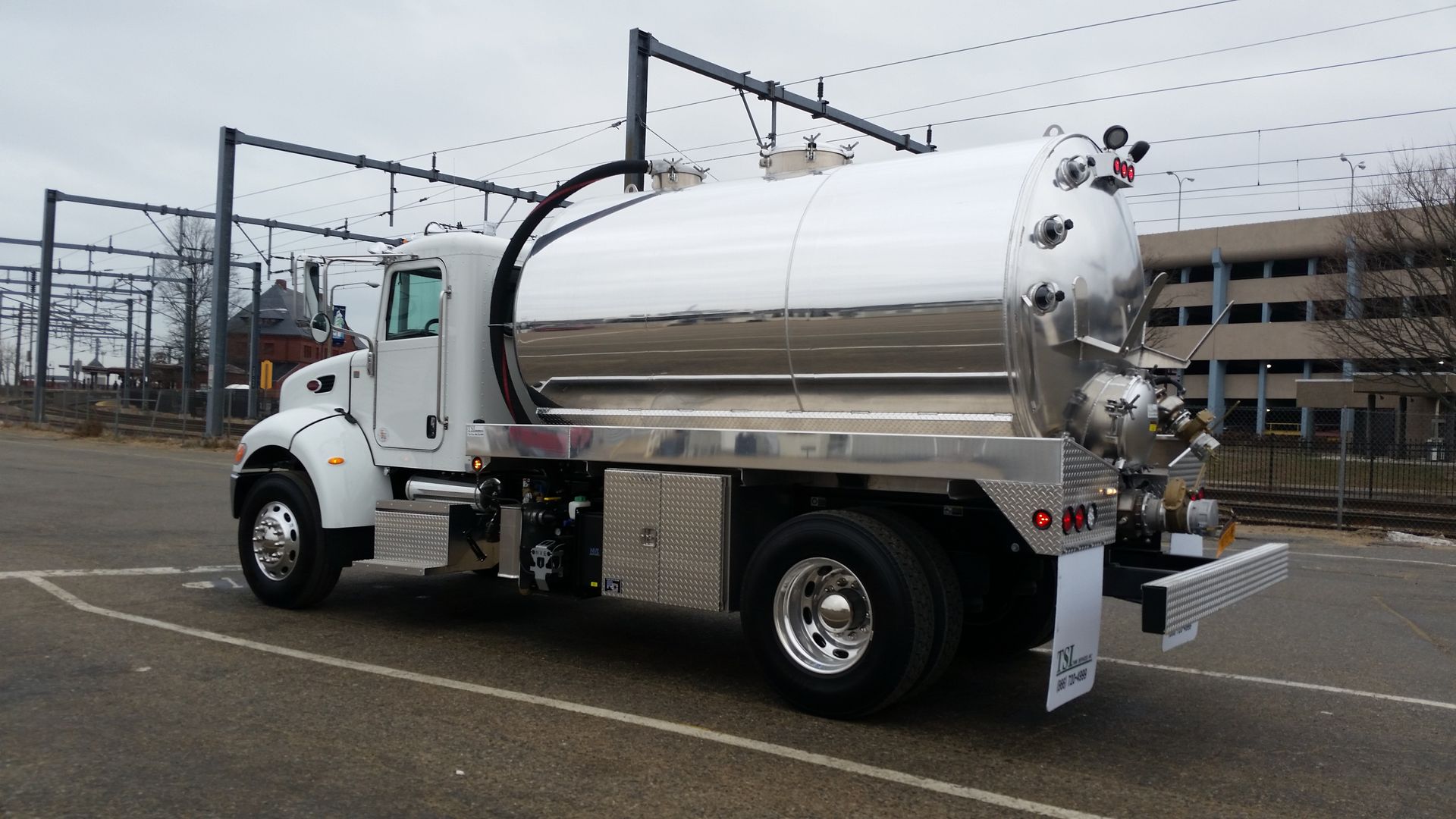 A silver vacuum truck is parked in a parking lot