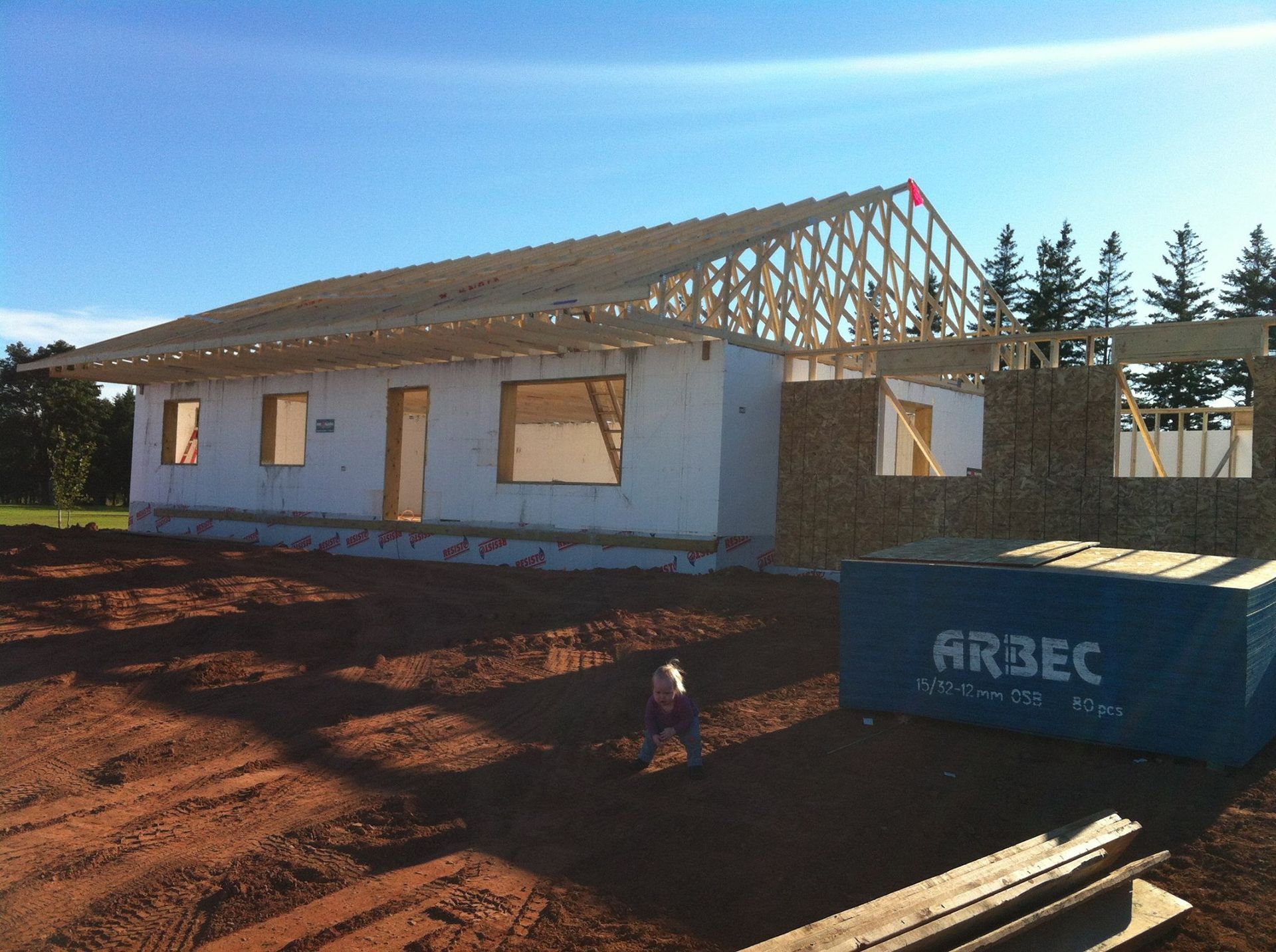 A blue arbec box sits in front of a house under construction