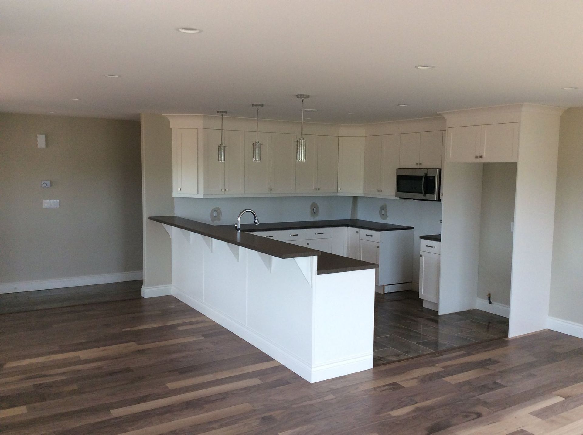 An empty kitchen with white cabinets and hardwood floors