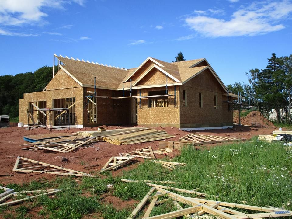 A house that is being built with a lot of wood in front of it