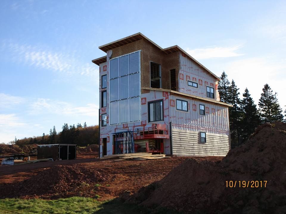A large house is being built in the middle of a dirt field.