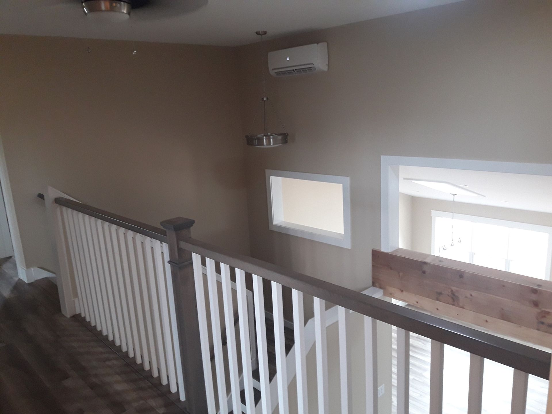 A hallway with a white railing and a ceiling fan.