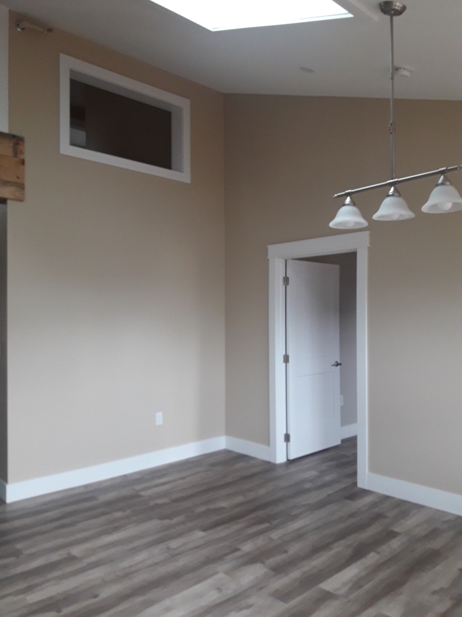 An empty room with a light fixture hanging from the ceiling and a window.