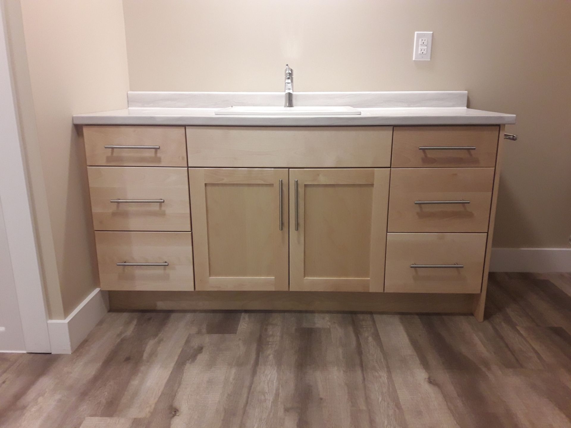 A bathroom vanity with wooden cabinets and drawers and a sink.