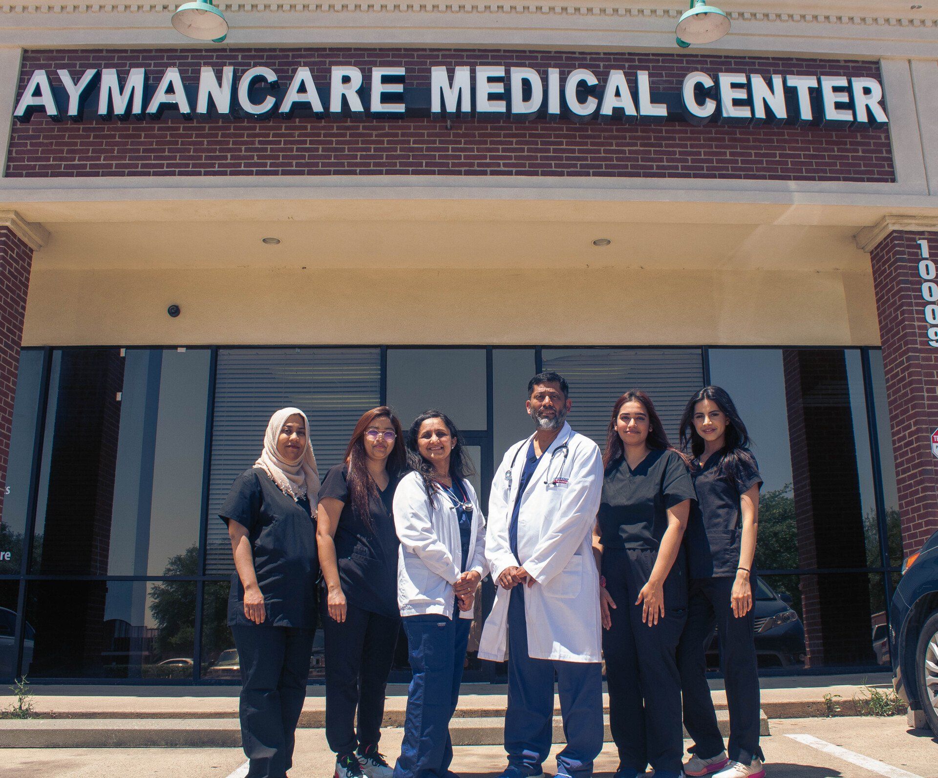 A group of doctors and nurses pose in front of the Aymancare Medical Center