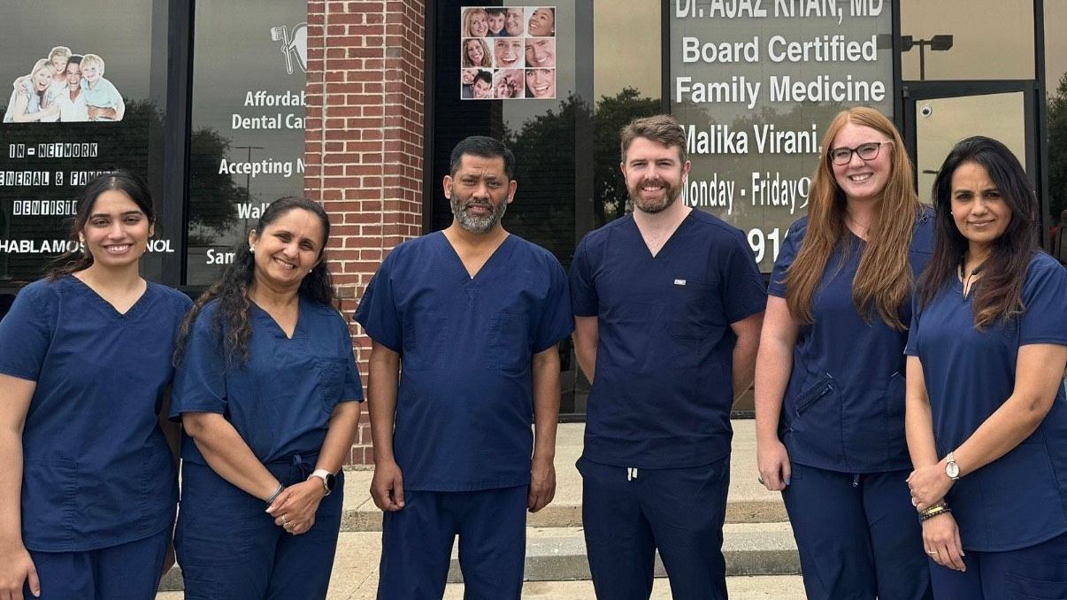 A group of people in scrubs are posing for a picture in front of a building.