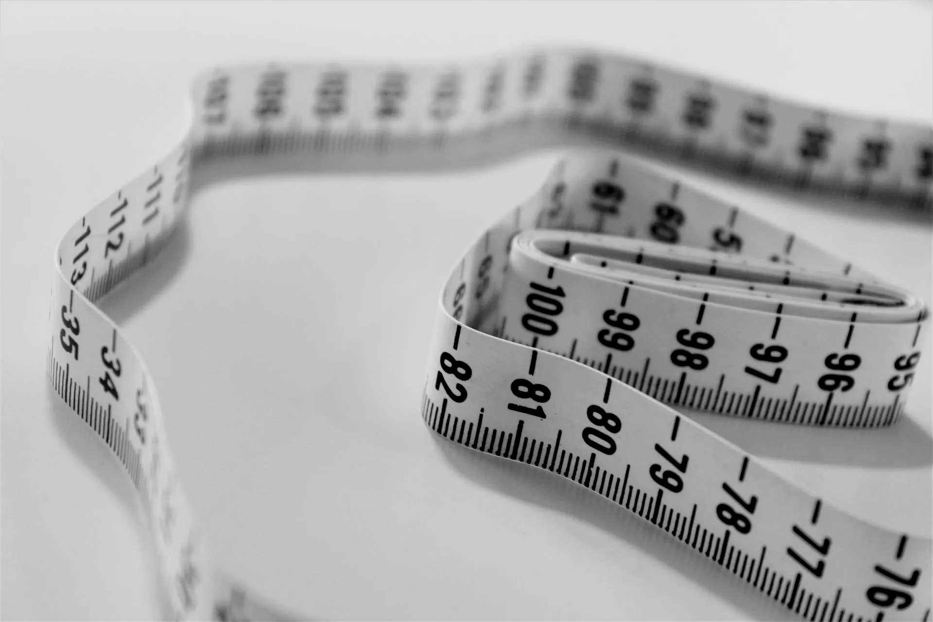 A white measuring tape with black numbers on it