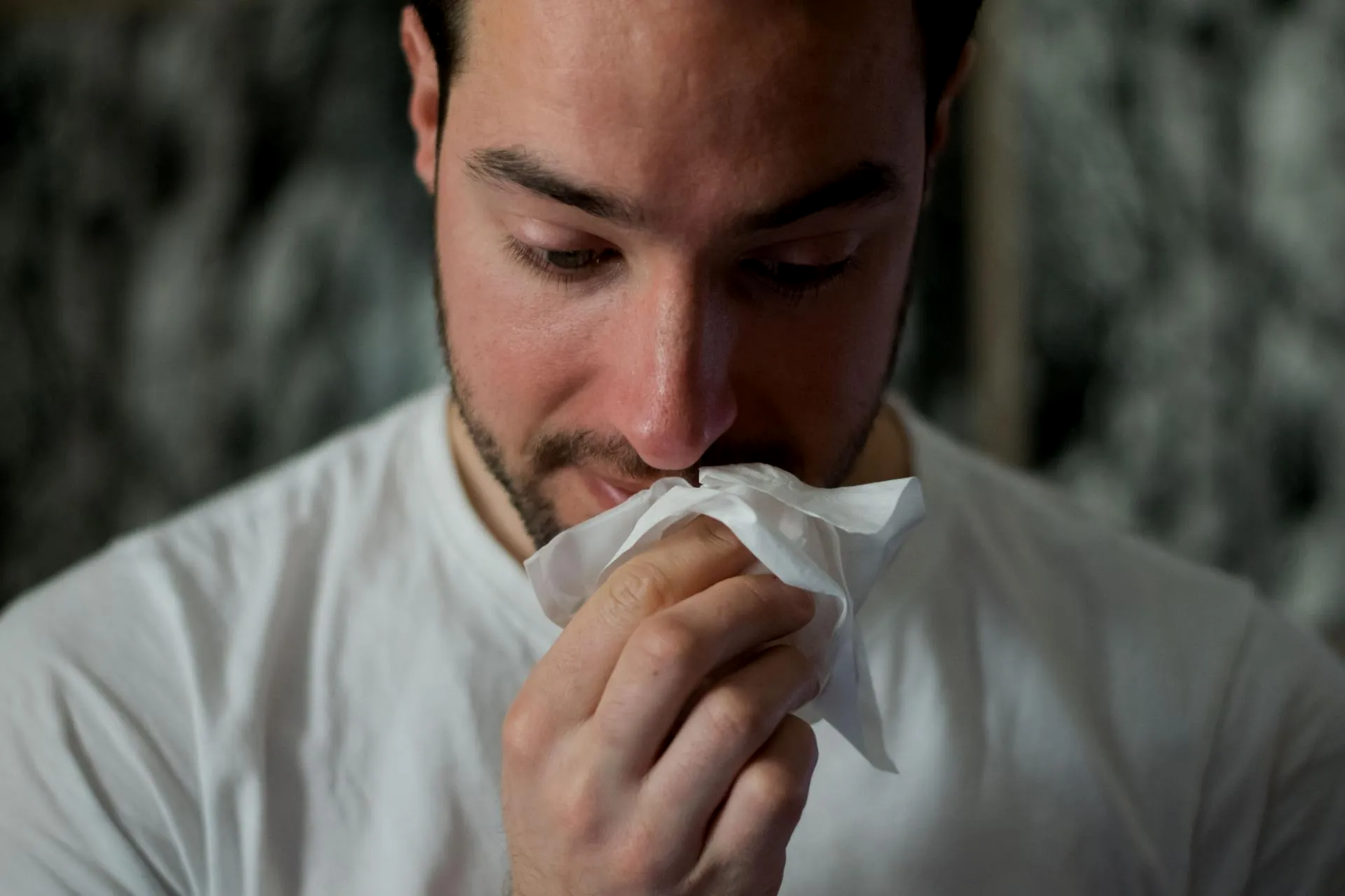 A man is blowing his nose into a napkin.