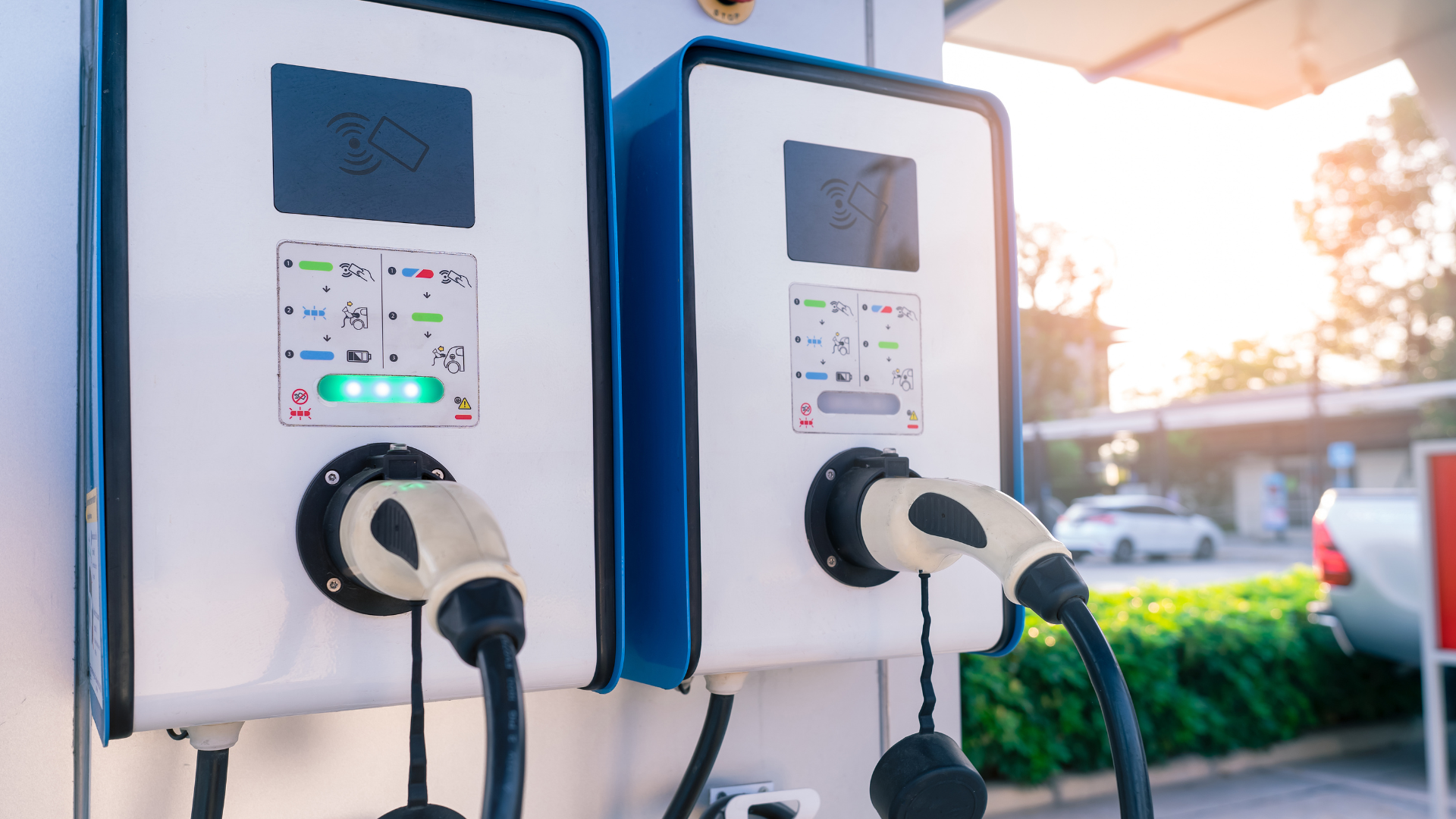 Two electric cars are being charged at a charging station.