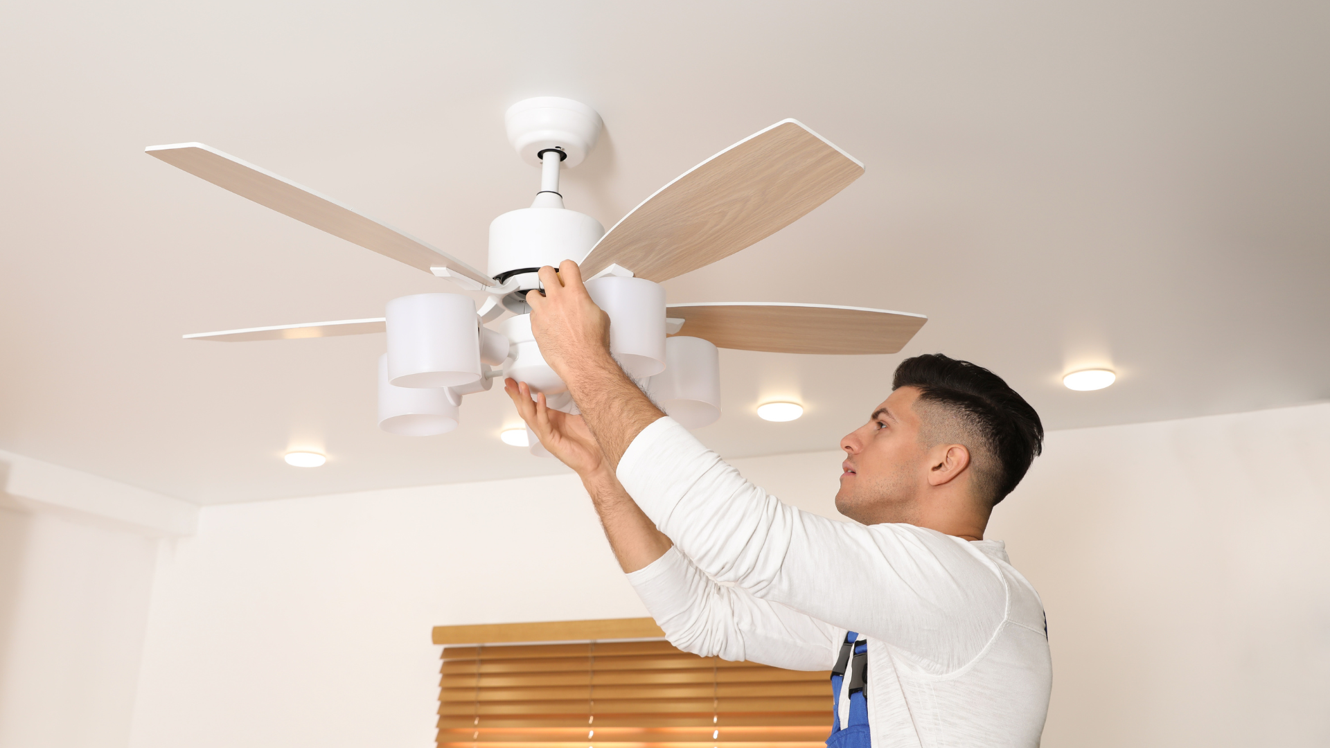 A man is installing a ceiling fan in a living room.