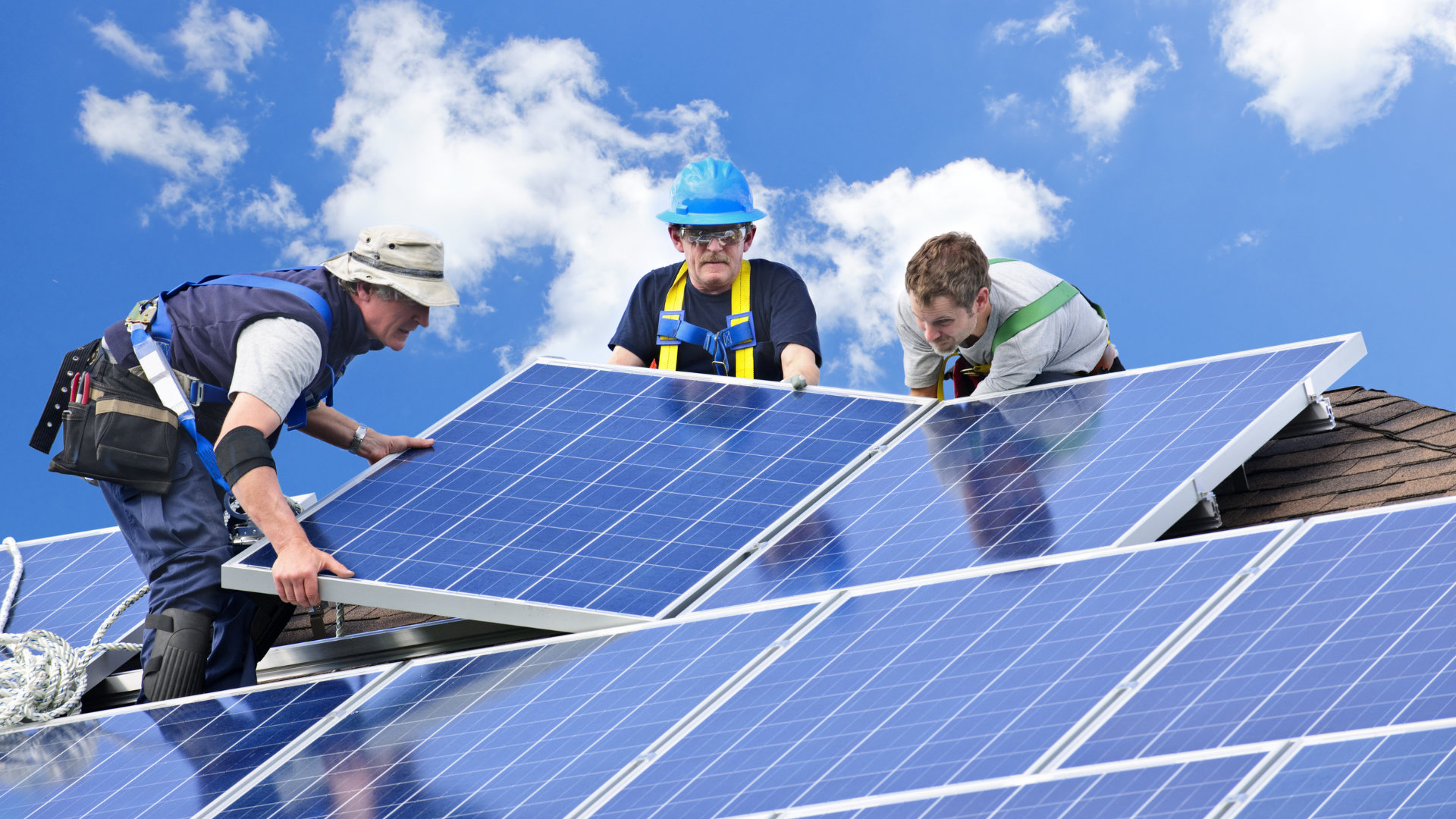 Three men are installing solar panels on a roof.