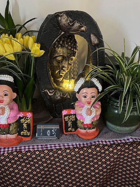 Buddhist shrine with statues, flowers, and a Buddha face with a light.