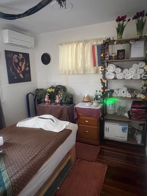 Massage room with a massage table, cabinet, and shelves with towels and decorations.