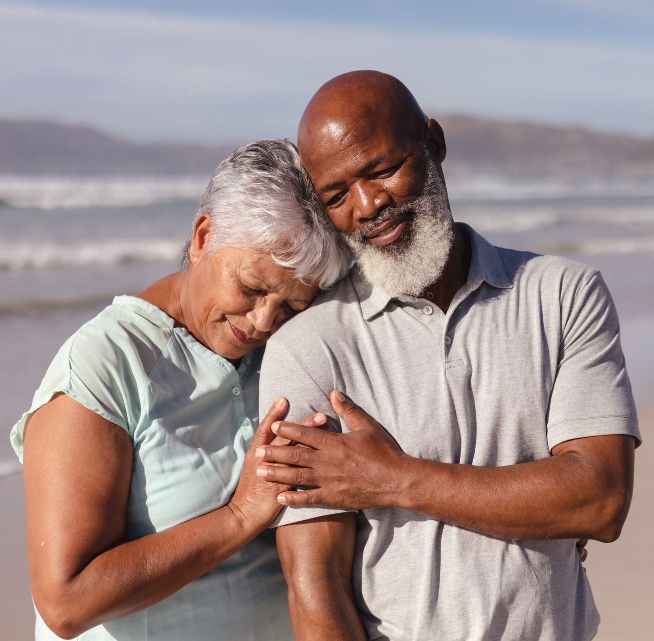 a man and woman walking on the beach holding hands