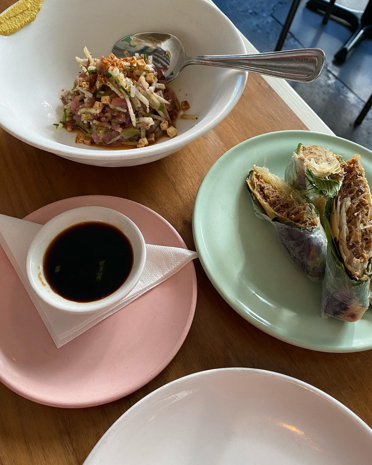 A table topped with plates of food and a bowl of sauce.