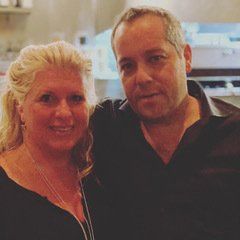 A man and a woman are posing for a picture together in a kitchen.