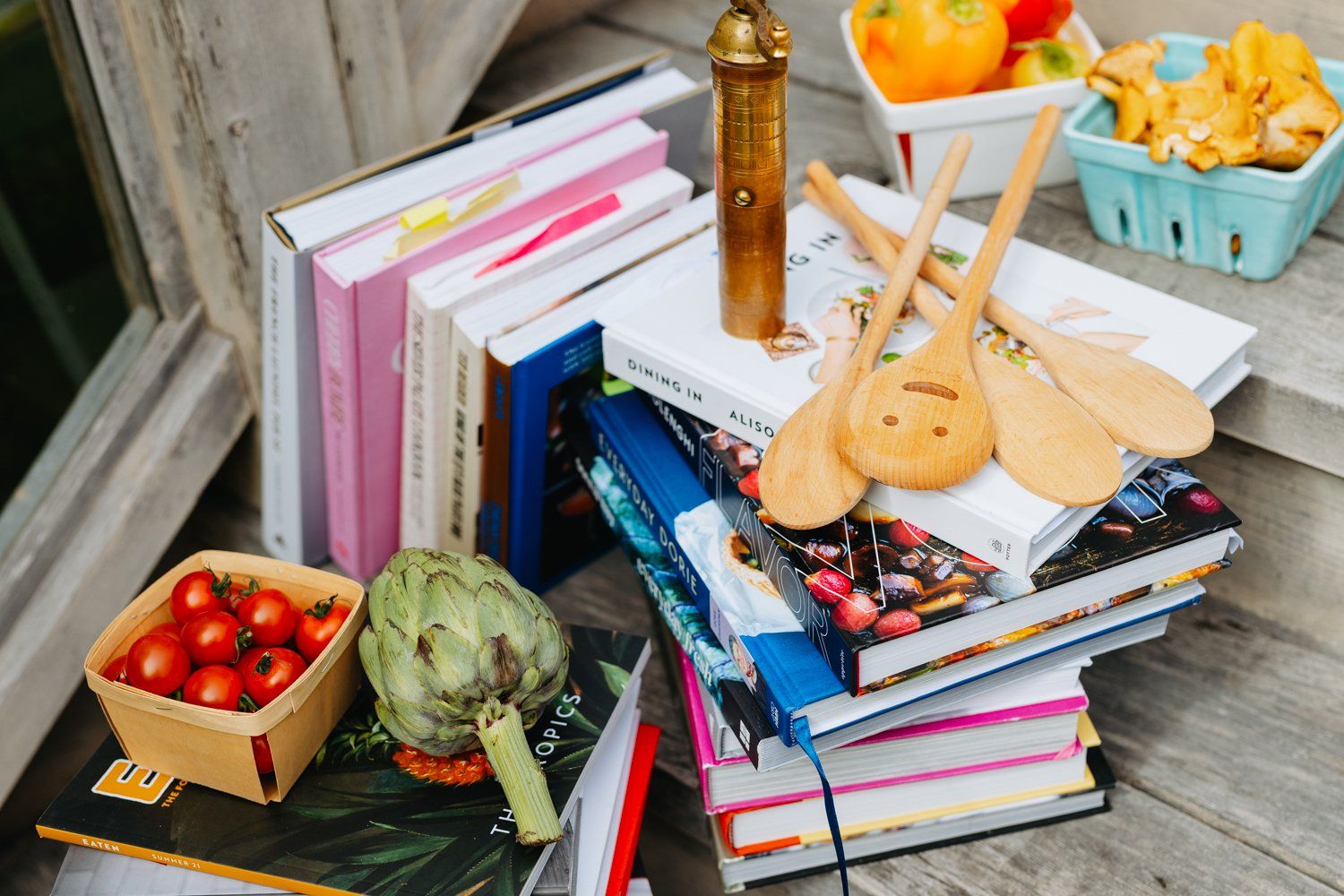A stack of books with wooden spoons on top of them.