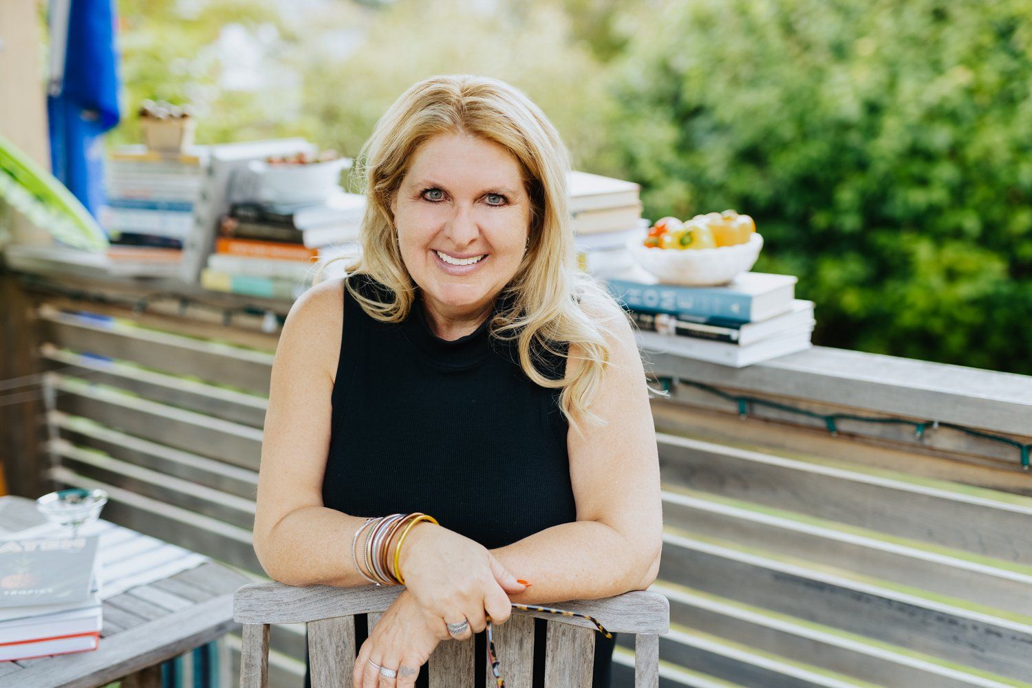 A woman is leaning on a wooden bench on a balcony.