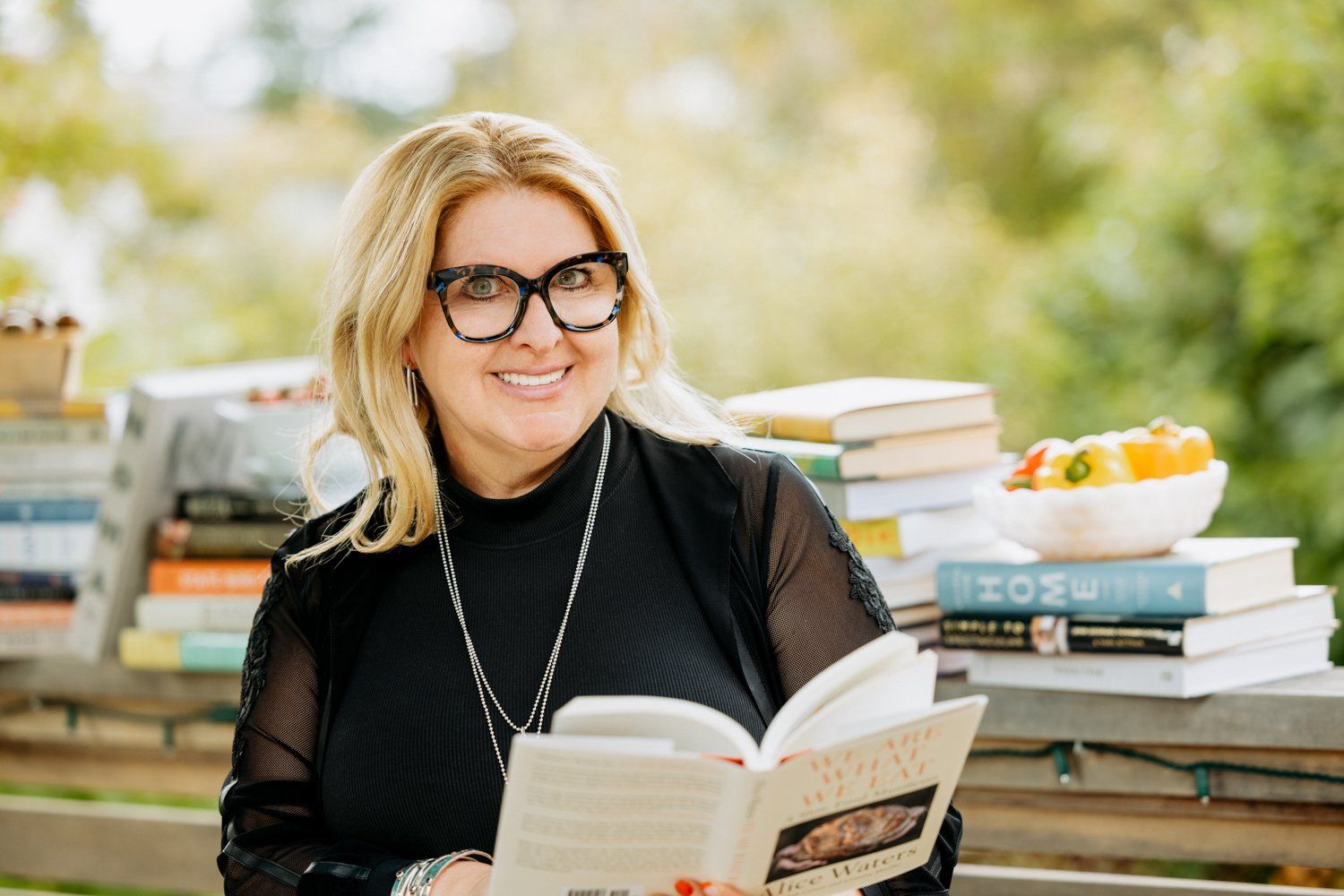 A woman is sitting on a porch reading a book.