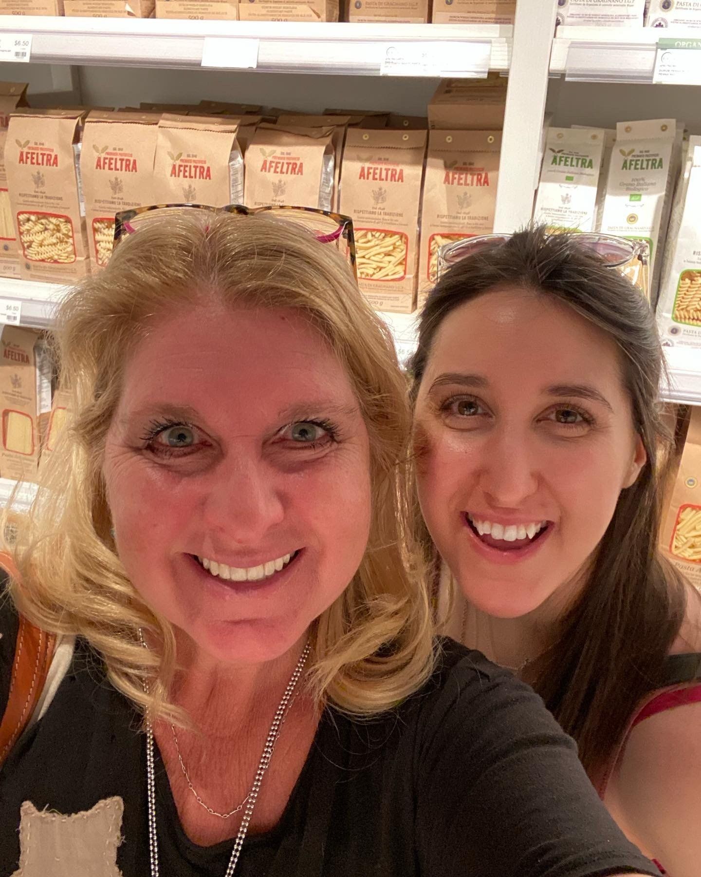 Two women are posing for a picture in a grocery store.