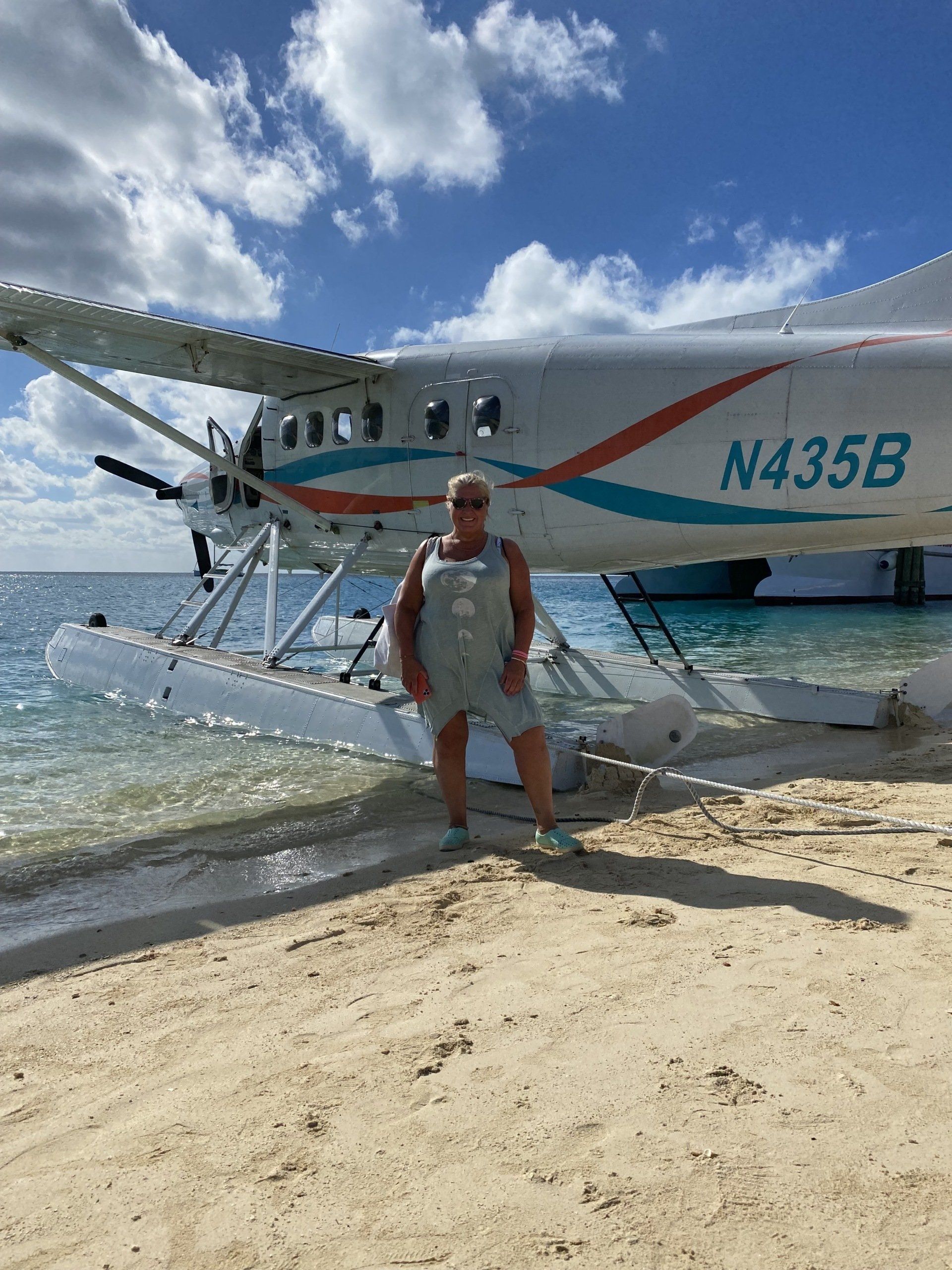 A man is standing on a beach next to a seaplane.