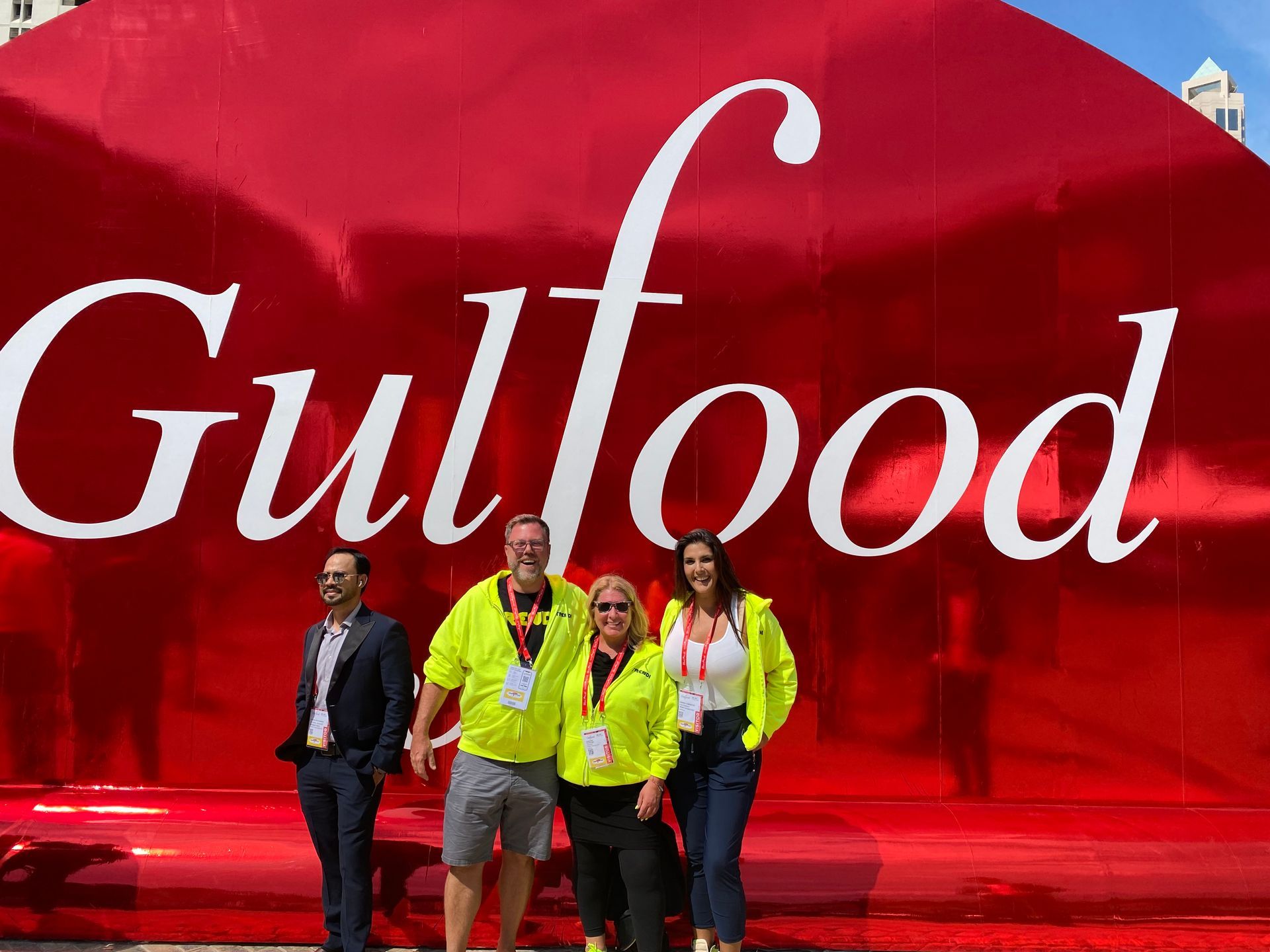 A group of people standing in front of a large red sign that says gulffood.