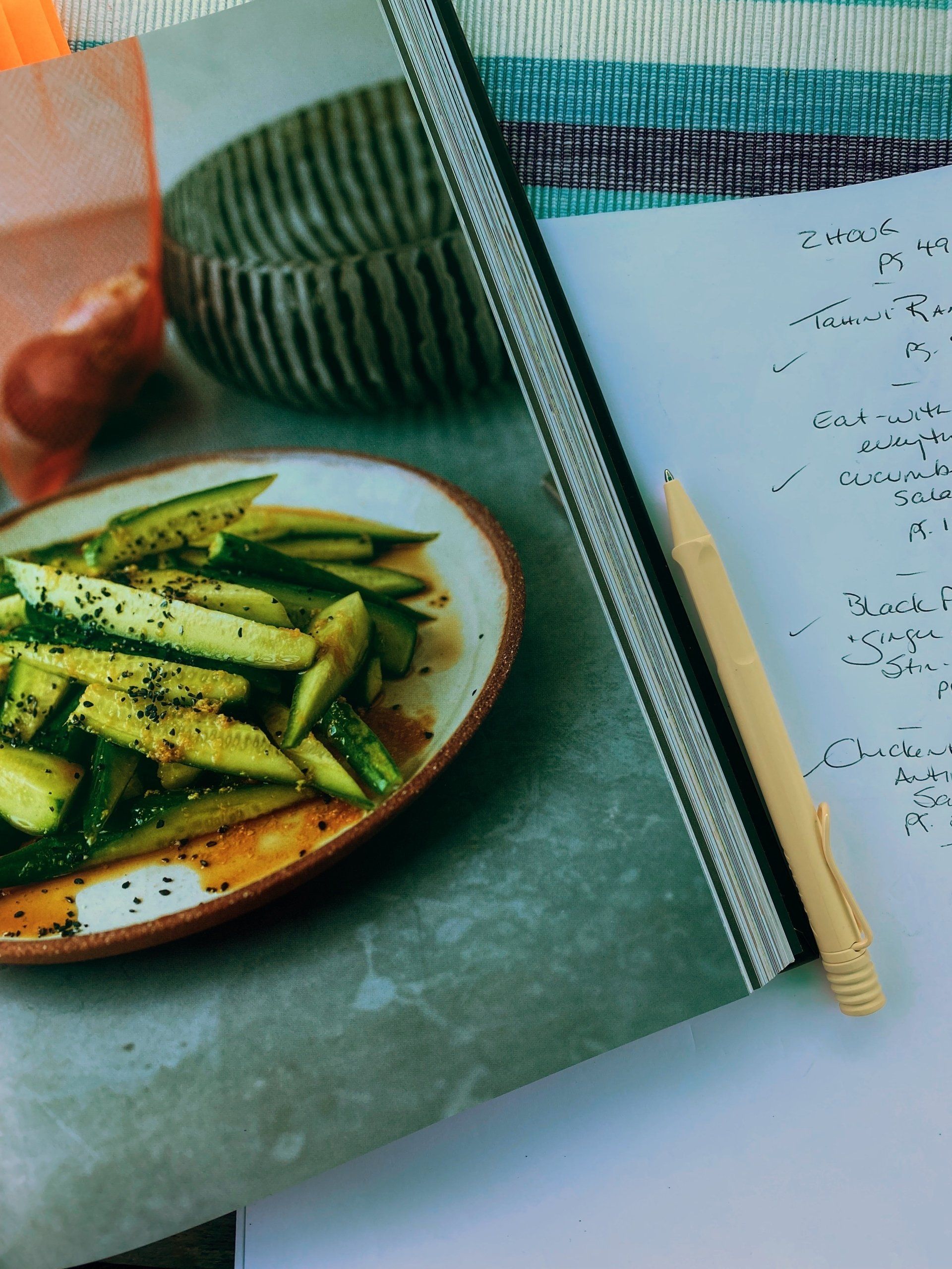 A recipe book with a plate of food and a pen next to it