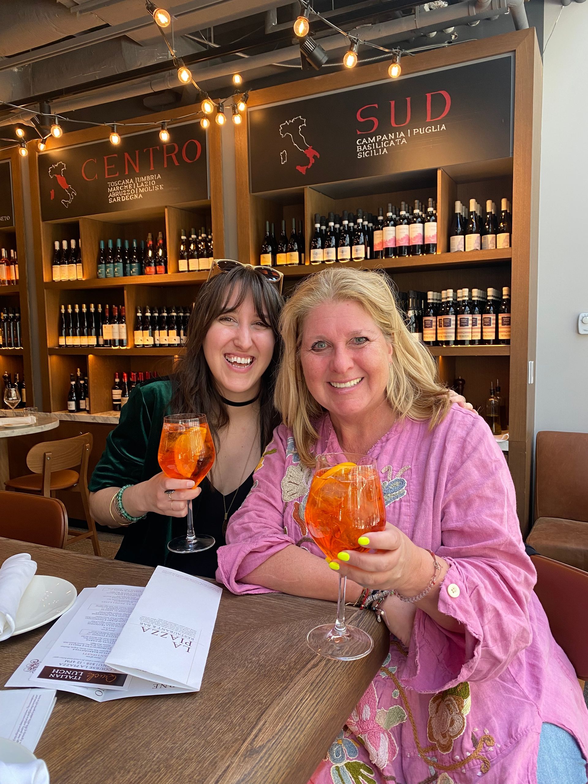 Two women are sitting at a table holding glasses of wine.