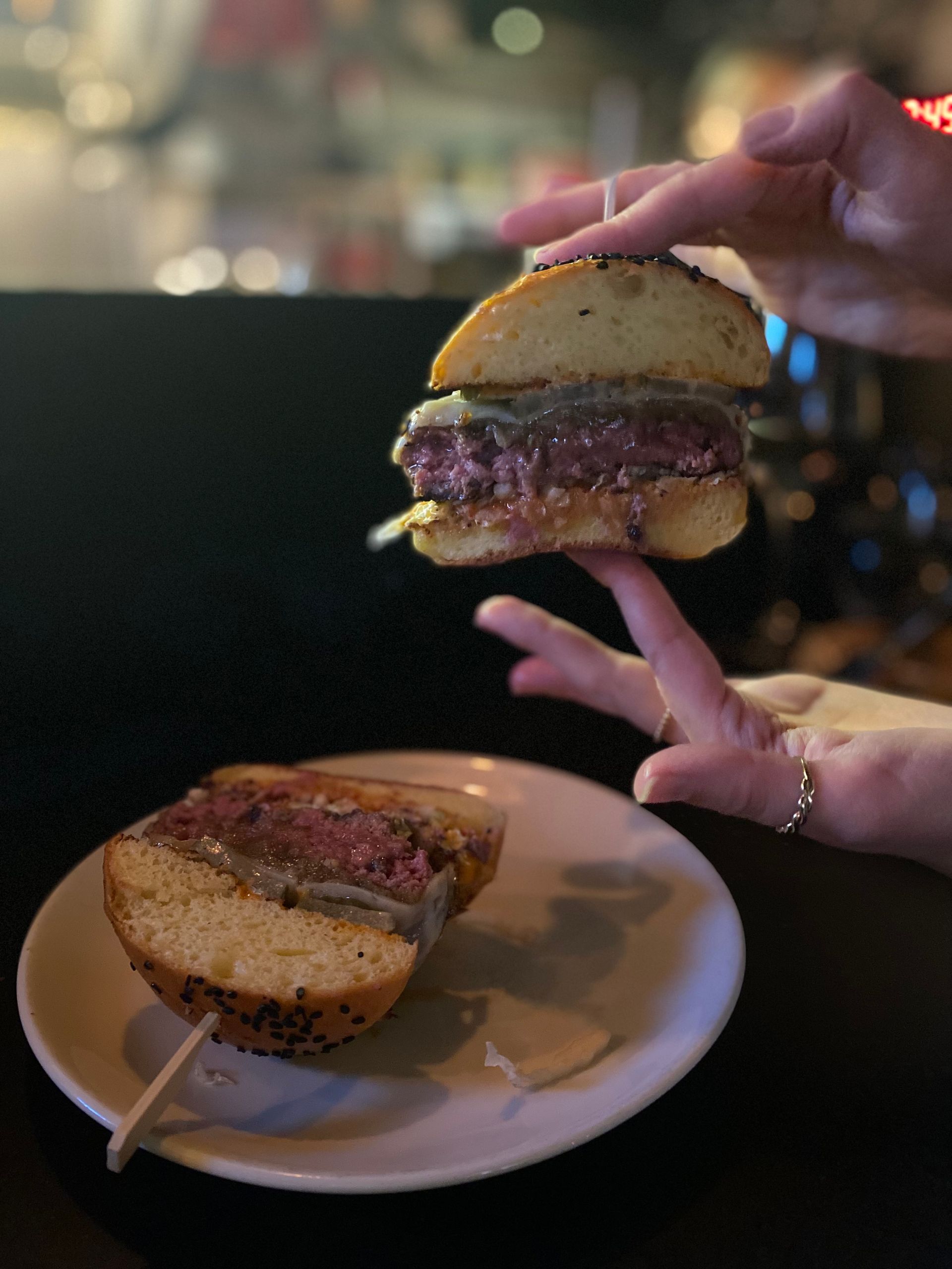 A person is holding a sandwich over a plate of food