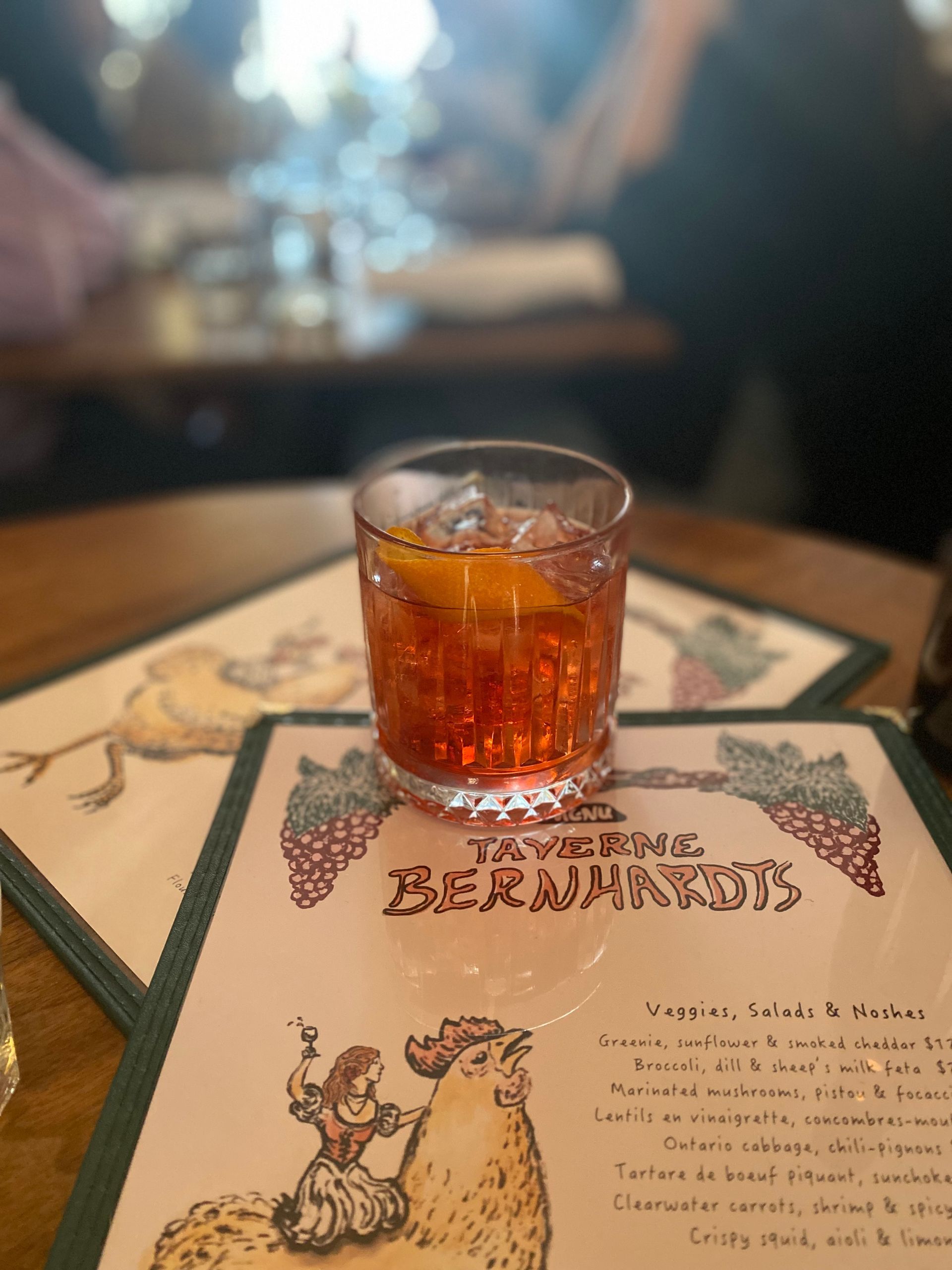 A glass of alcohol is sitting on top of a restaurant menu.