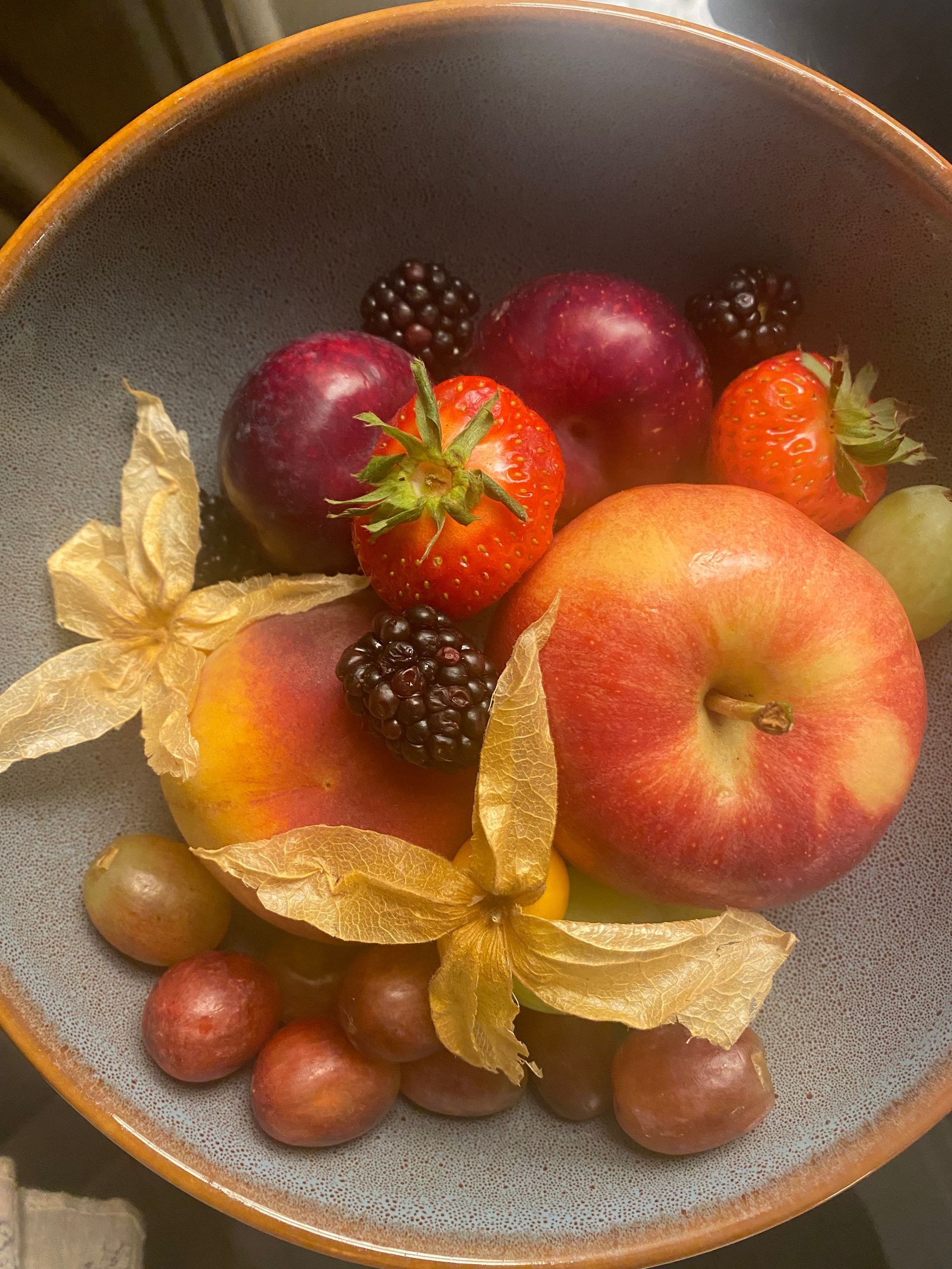 A bowl filled with apples , strawberries , blackberries and other fruits