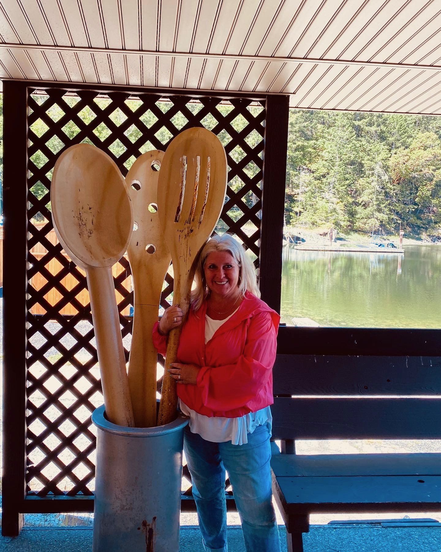 A woman is standing next to a bucket of wooden spoons.