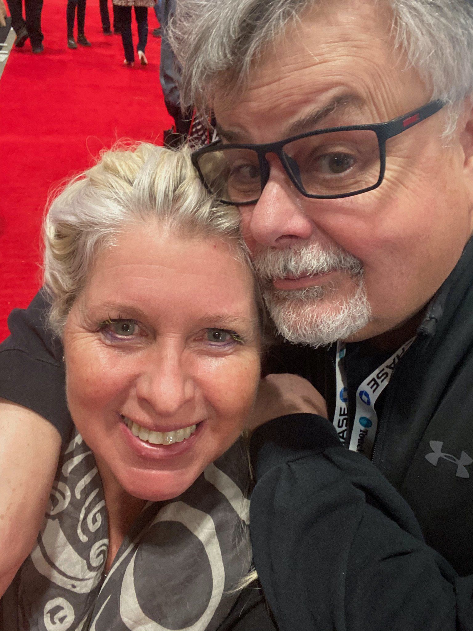 A man and a woman are posing for a picture on a red carpet.