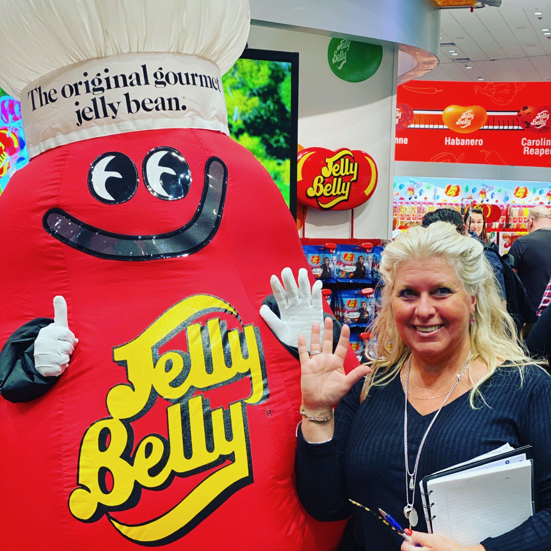A woman standing next to a jelly belly mascot