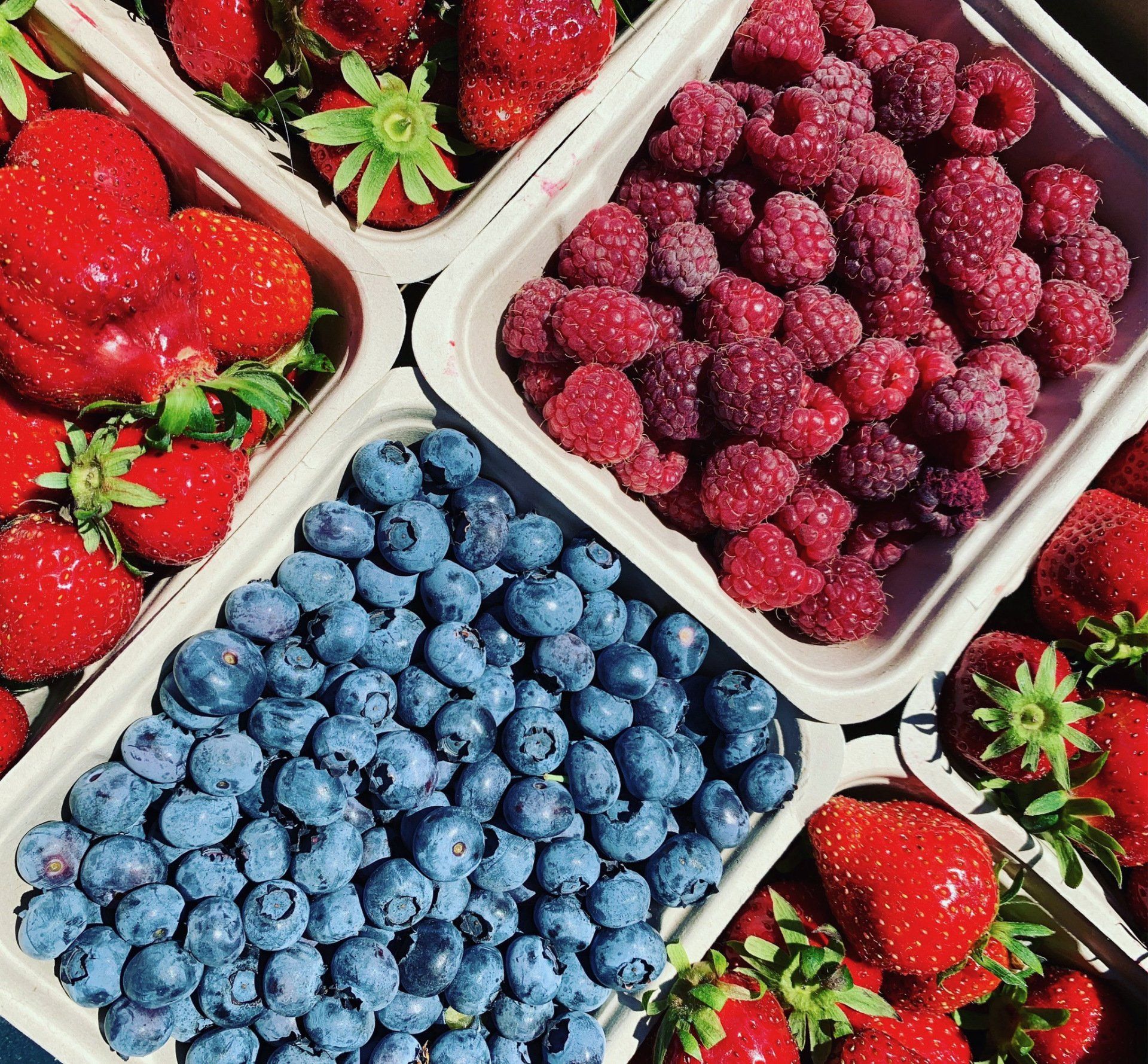 Strawberries blueberries raspberries and other berries in containers