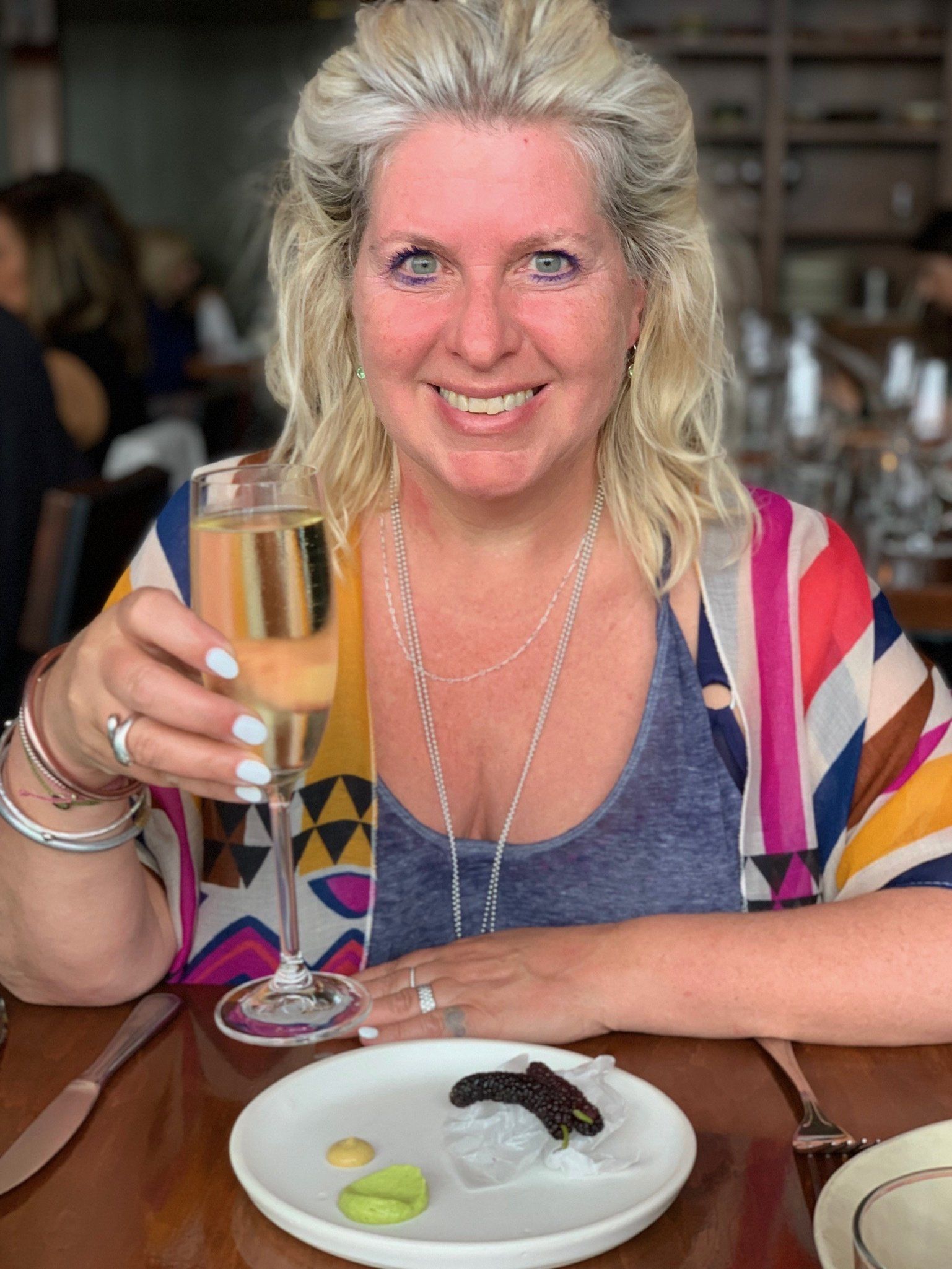 A woman is sitting at a table holding a glass of champagne.