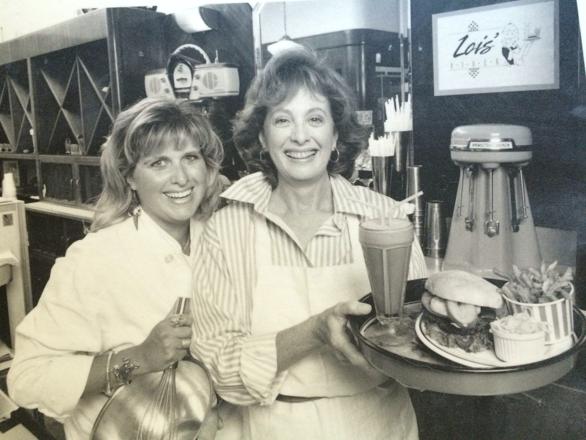 Two women standing in front of a sign that says lois