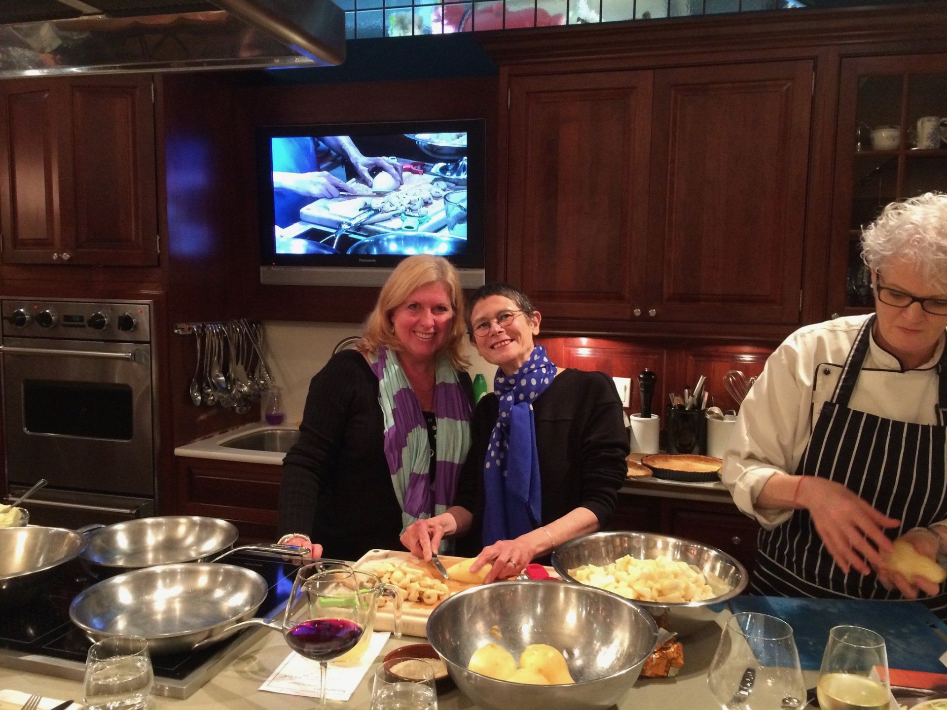 Two women and a man are standing in a kitchen preparing food
