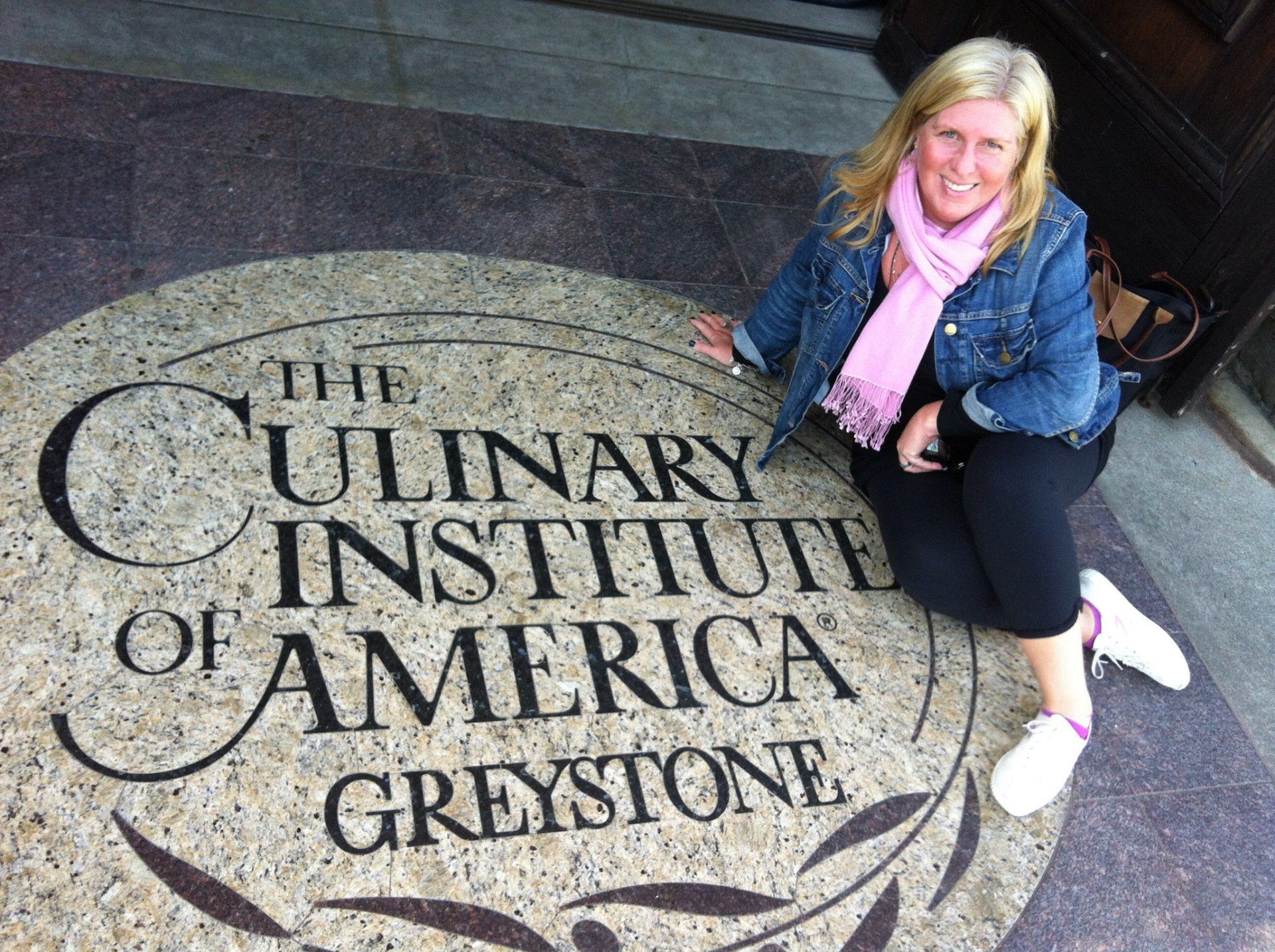 A woman is kneeling in front of the culinary institute of america greystone