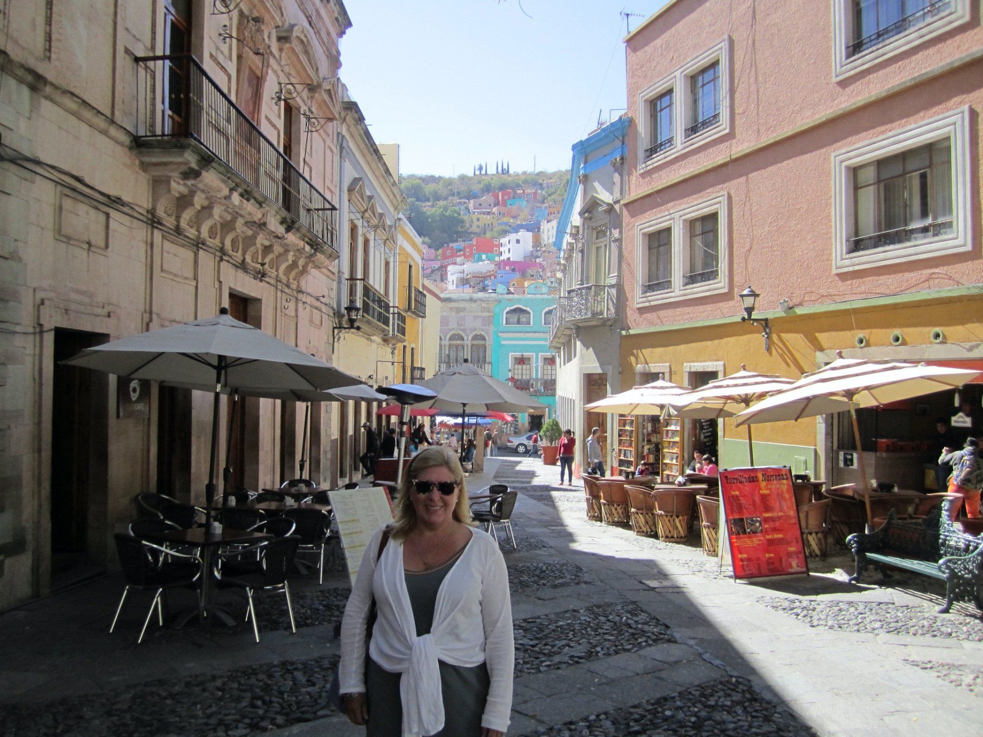 A woman is standing in a narrow street between two buildings