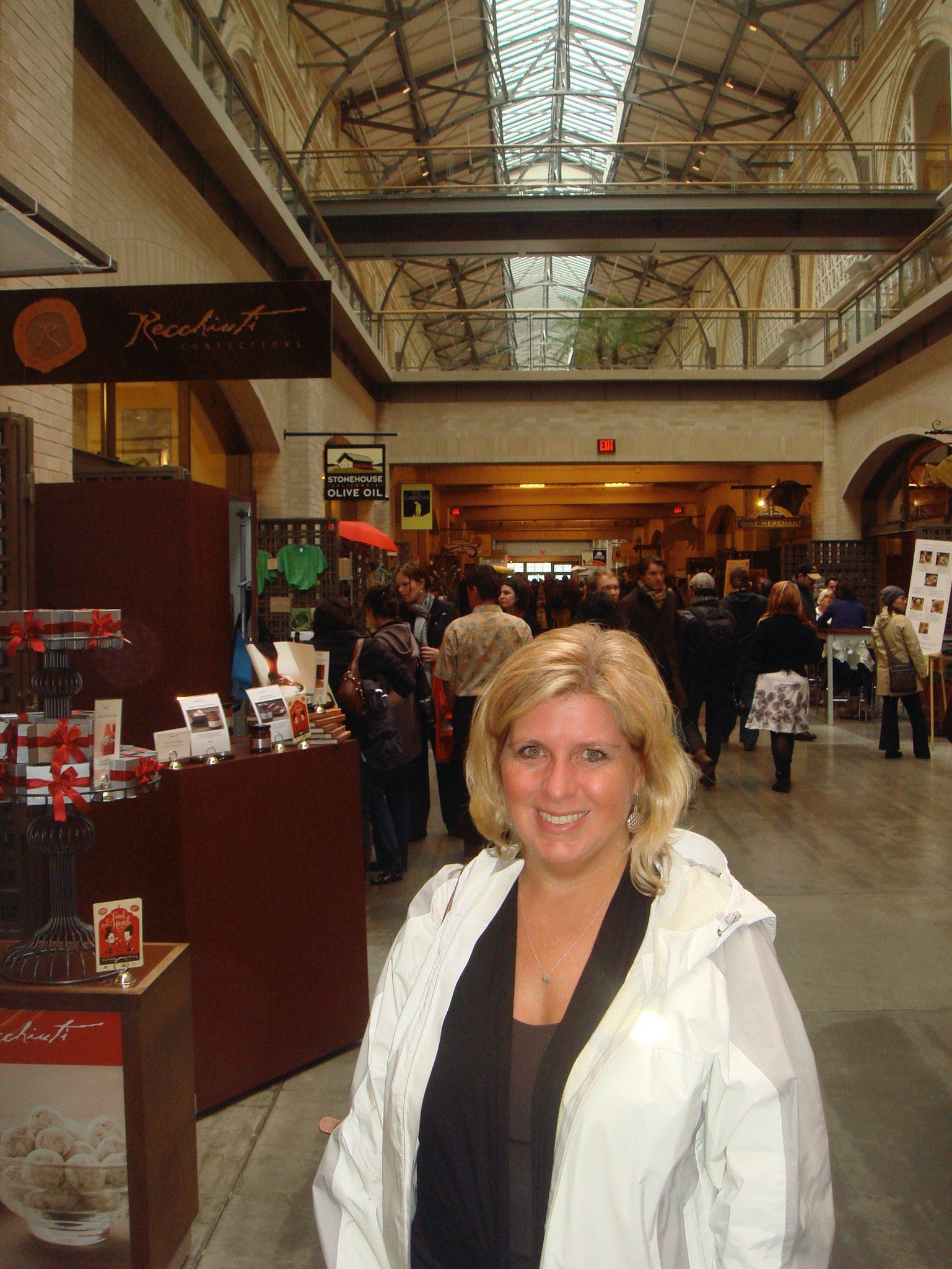A woman in a white jacket is standing in a shopping mall