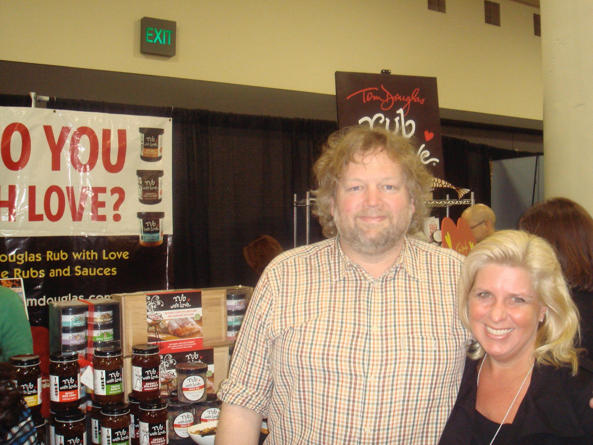 A man and woman pose in front of a sign that says